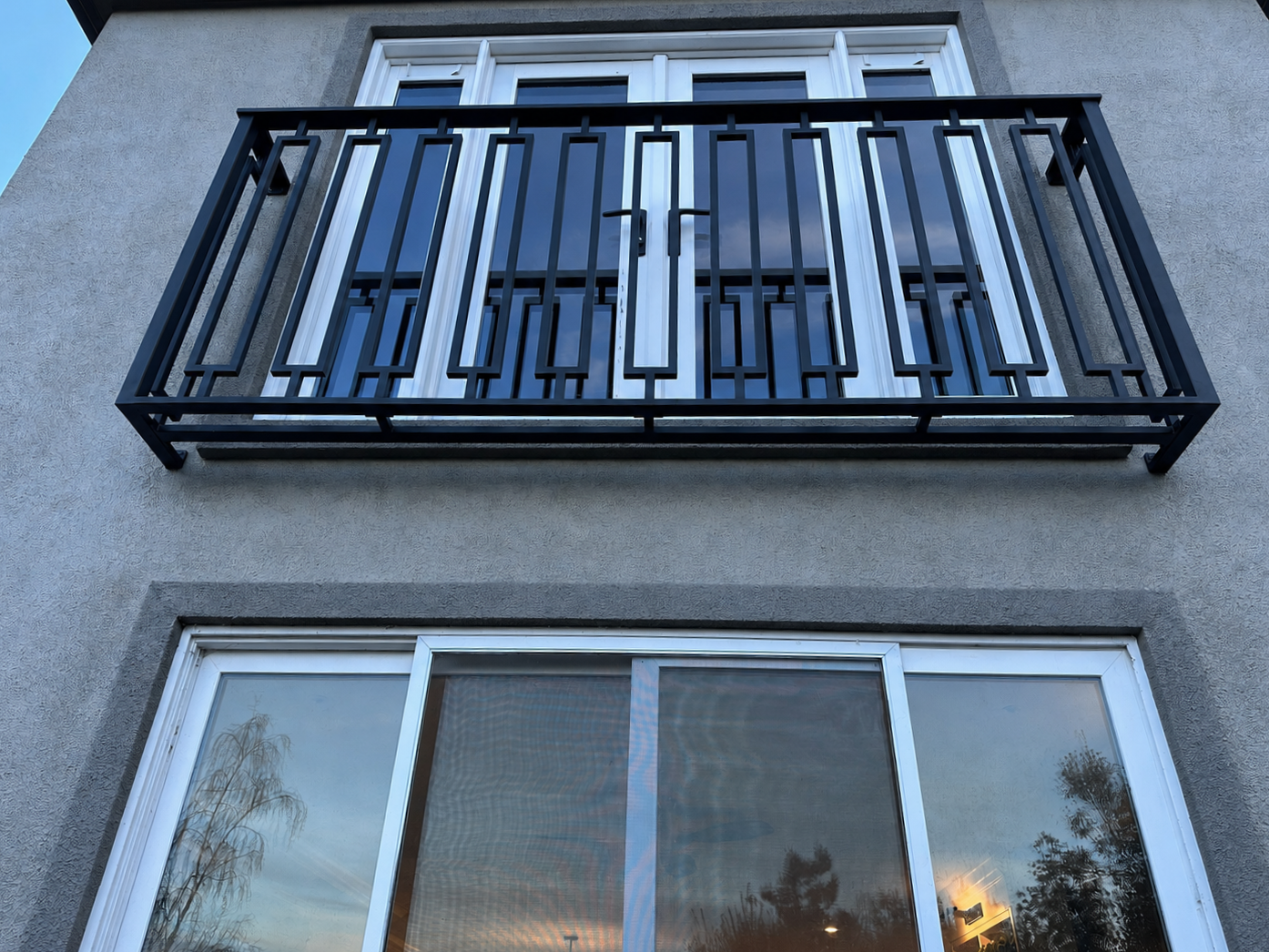 Close view of black geometric balcony railing on gray stucco home