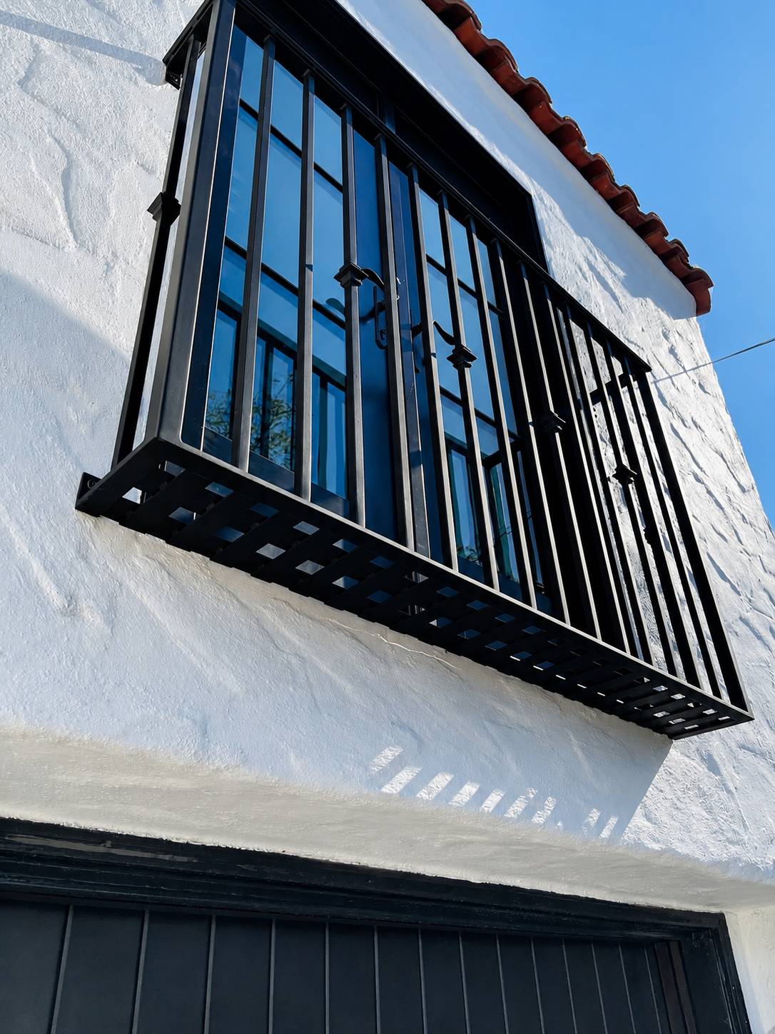Black window balcony guard on white stucco wall