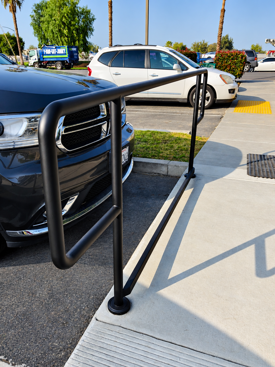 Commercial black pipe handrail along accessible curb ramp