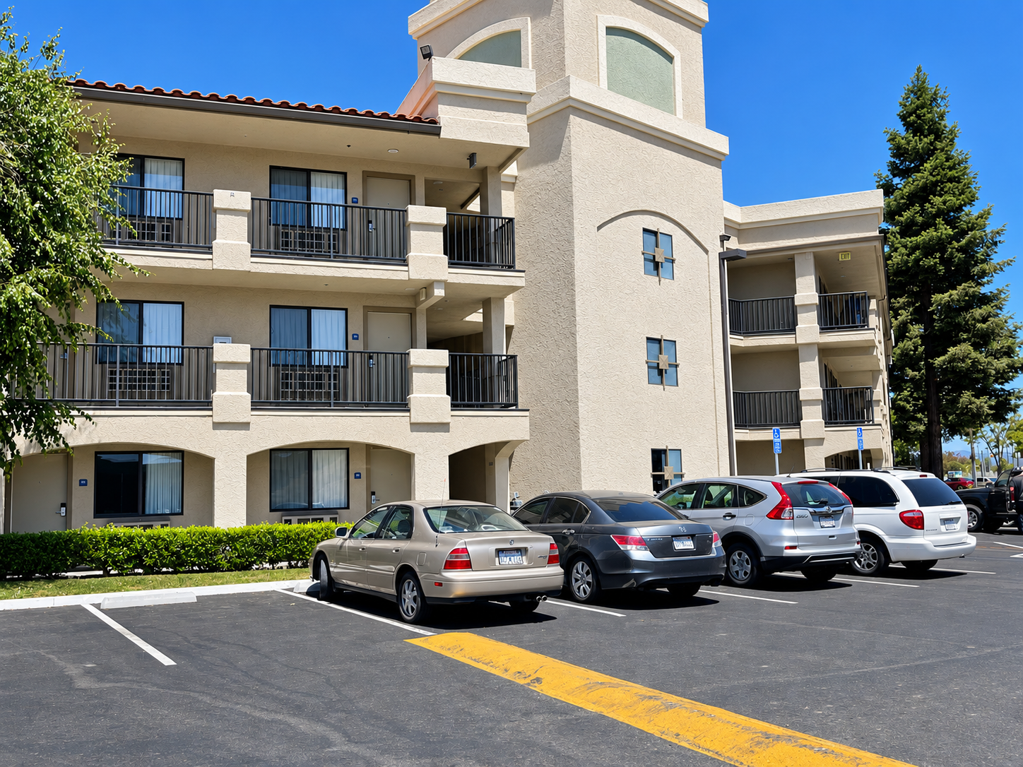 Commercial hotel exterior with black balcony railings and parking area