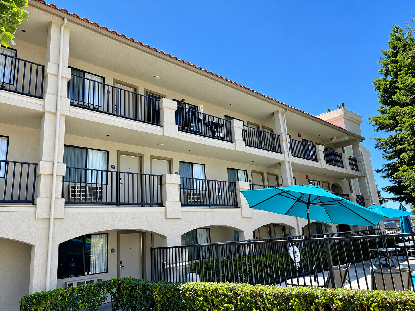 Commercial hotel facade with black balcony railings and pool fencing