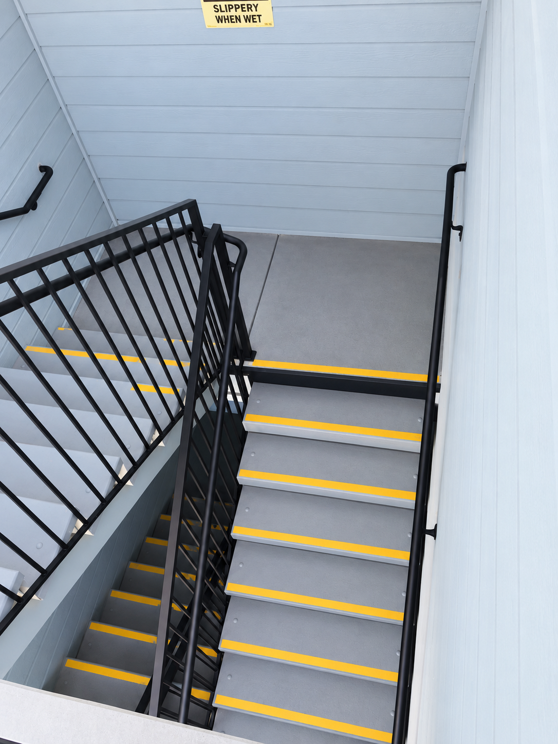 Commercial stairwell with black railing and wall-mounted handrail