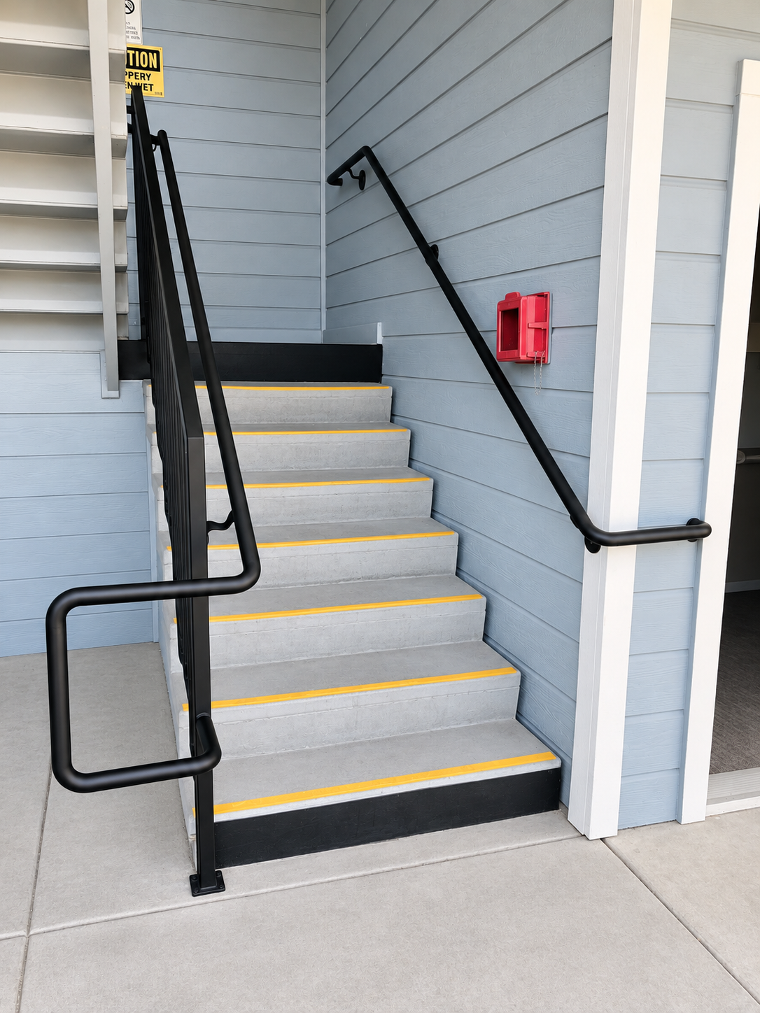 Commercial exterior stair with black handrails and red fire box