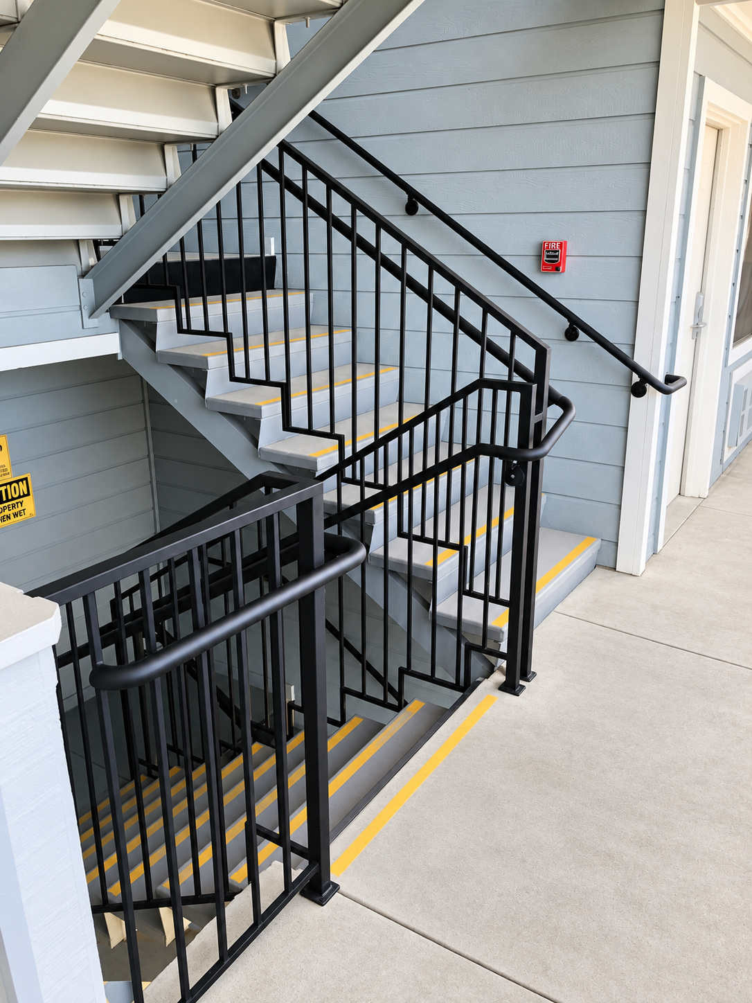 Commercial stair landing with black railings and wall handrail