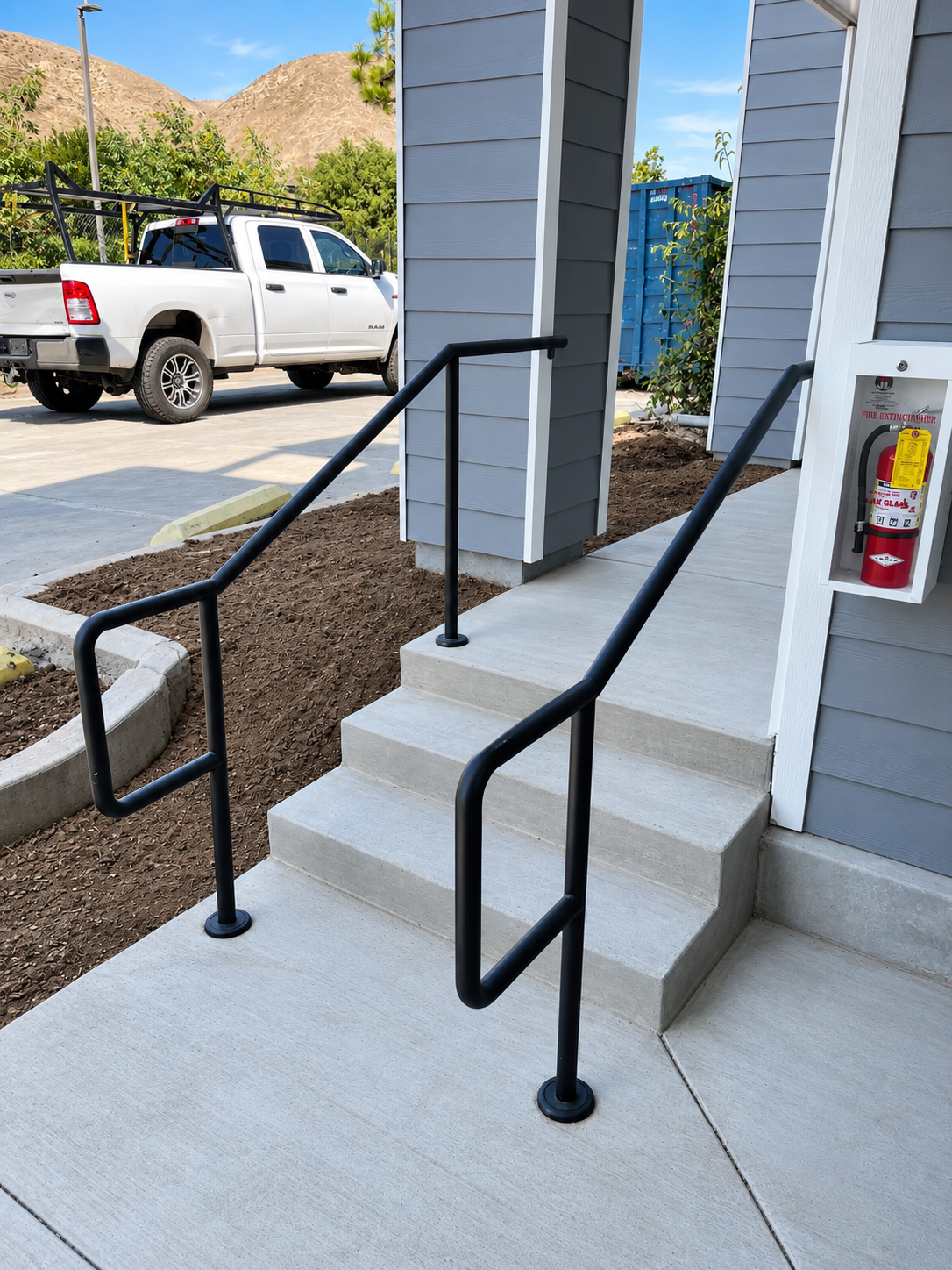 Commercial concrete entry steps with black pipe handrails