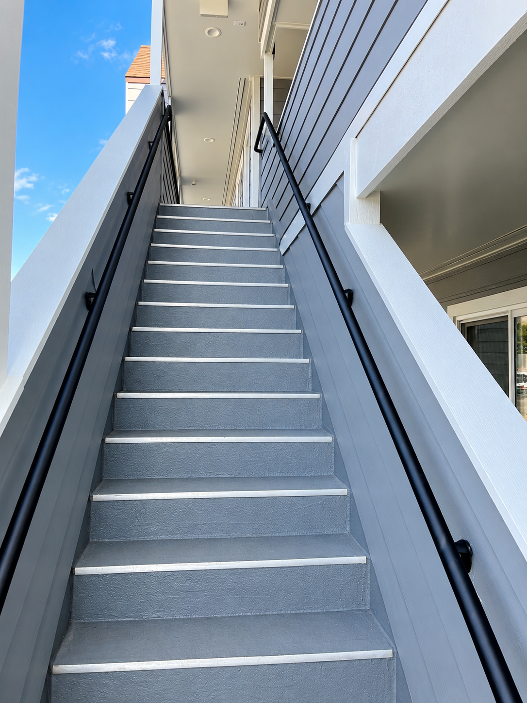 Commercial stairway with black wall-mounted handrails on both sides