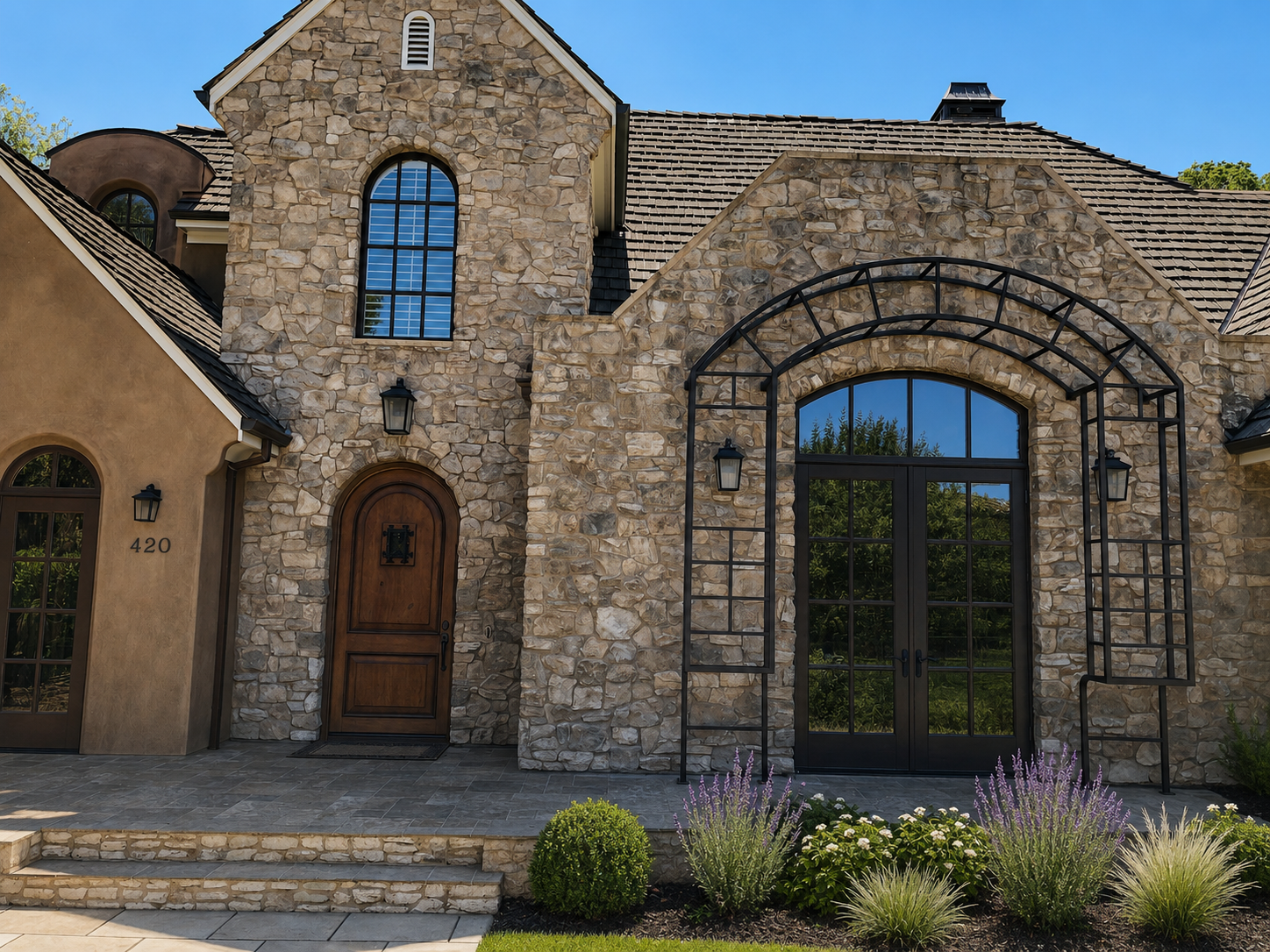 Stone home entry with black arched metal trellis and doors