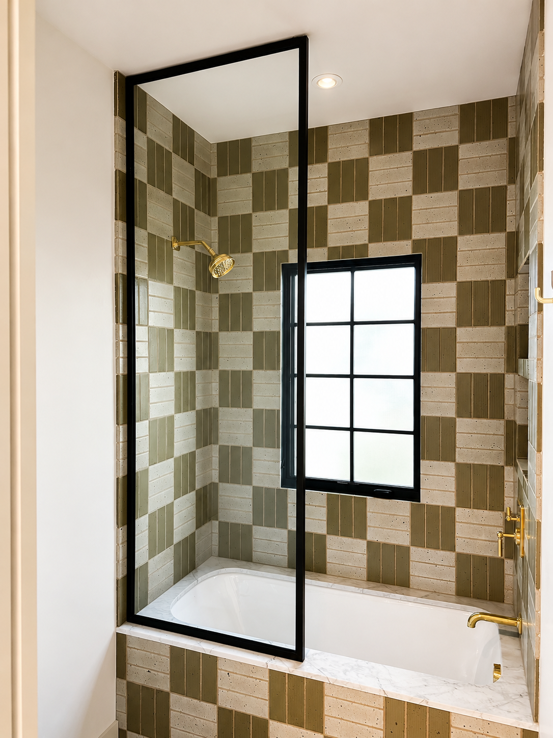 Open black metal and glass bath enclosure above tub with brass fixtures
