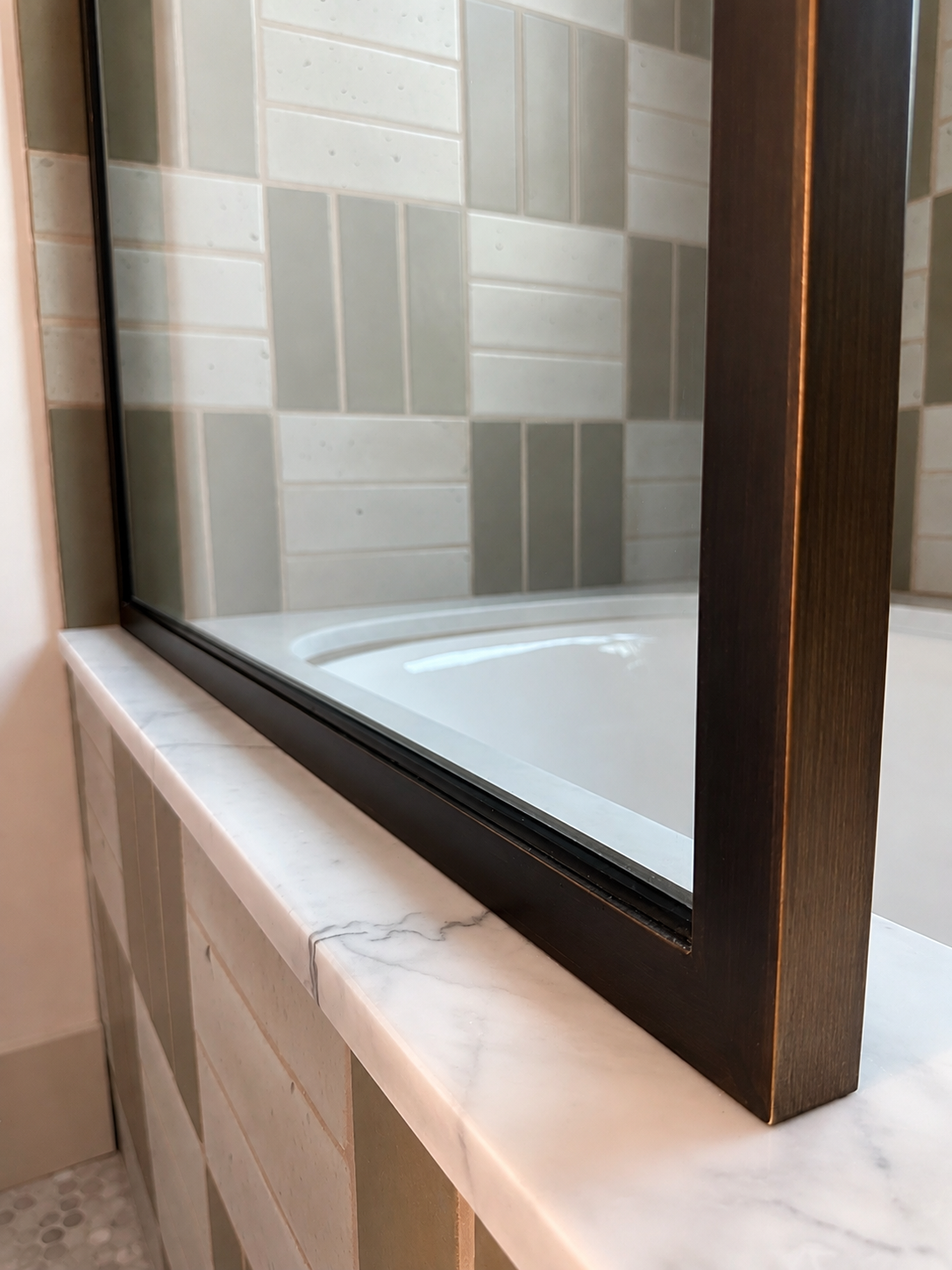 Close detail of black metal bath enclosure frame on marble ledge