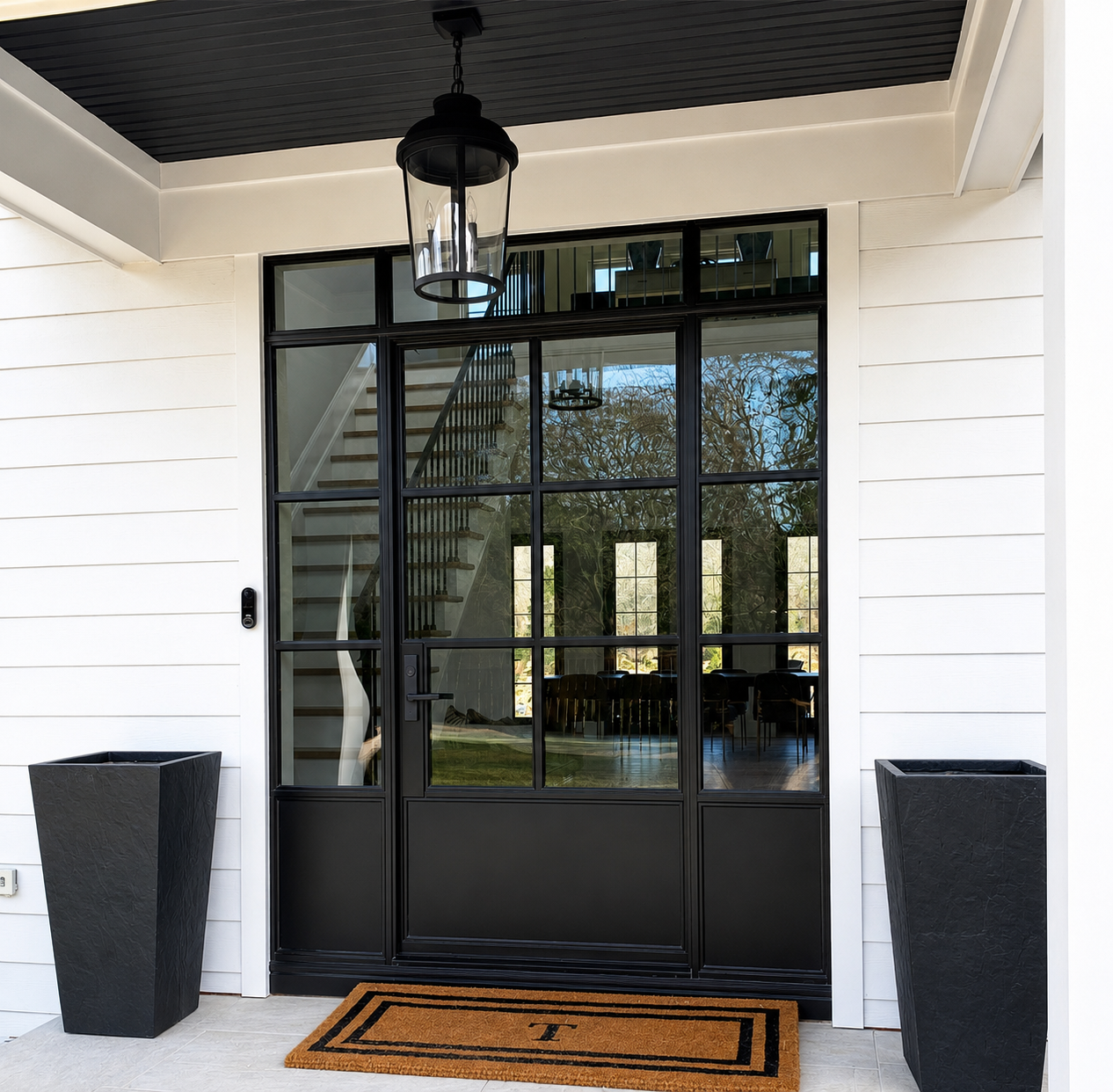Black metal and glass entry door with sidelights on a white exterior