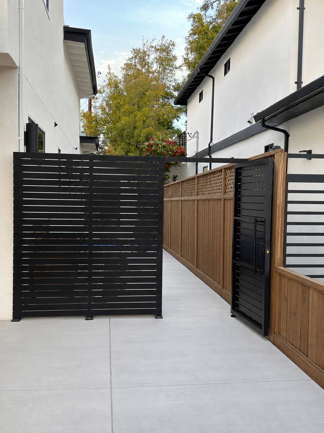 Black horizontal slat side gate with matching pedestrian gate and wood fence