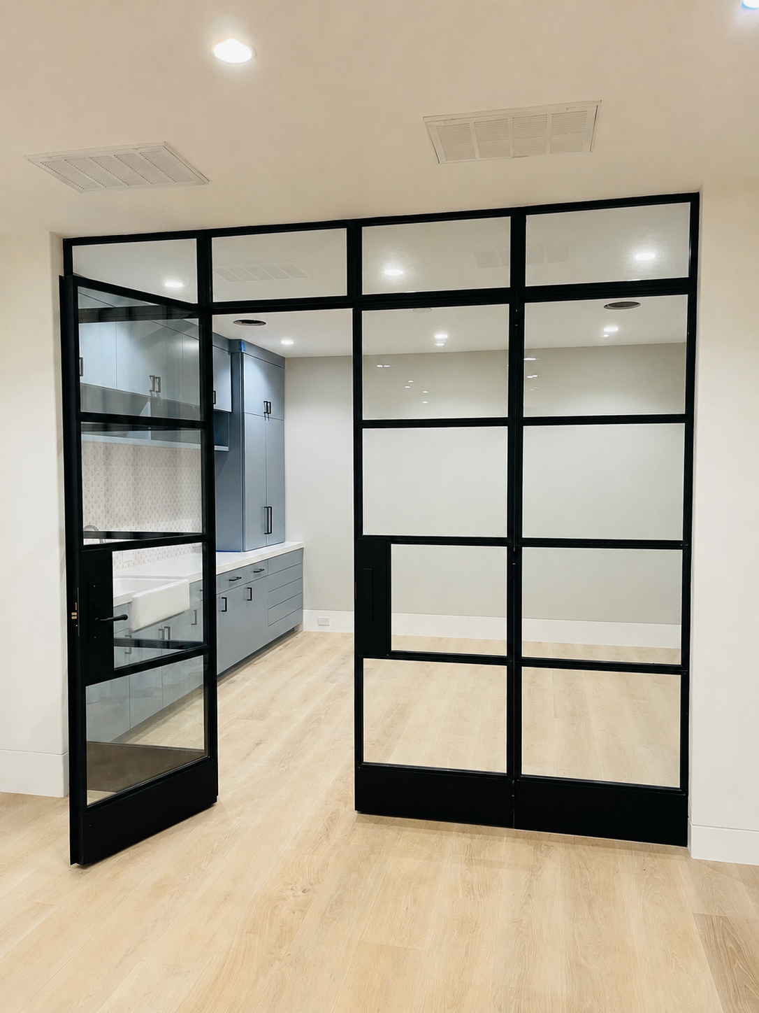 Black metal and glass interior grid doors opening into a kitchen