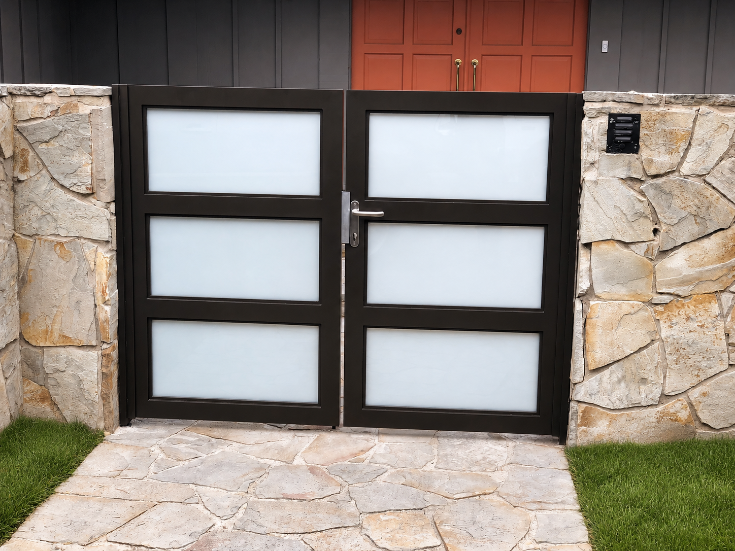 Black metal gate with frosted glass panels between stone columns