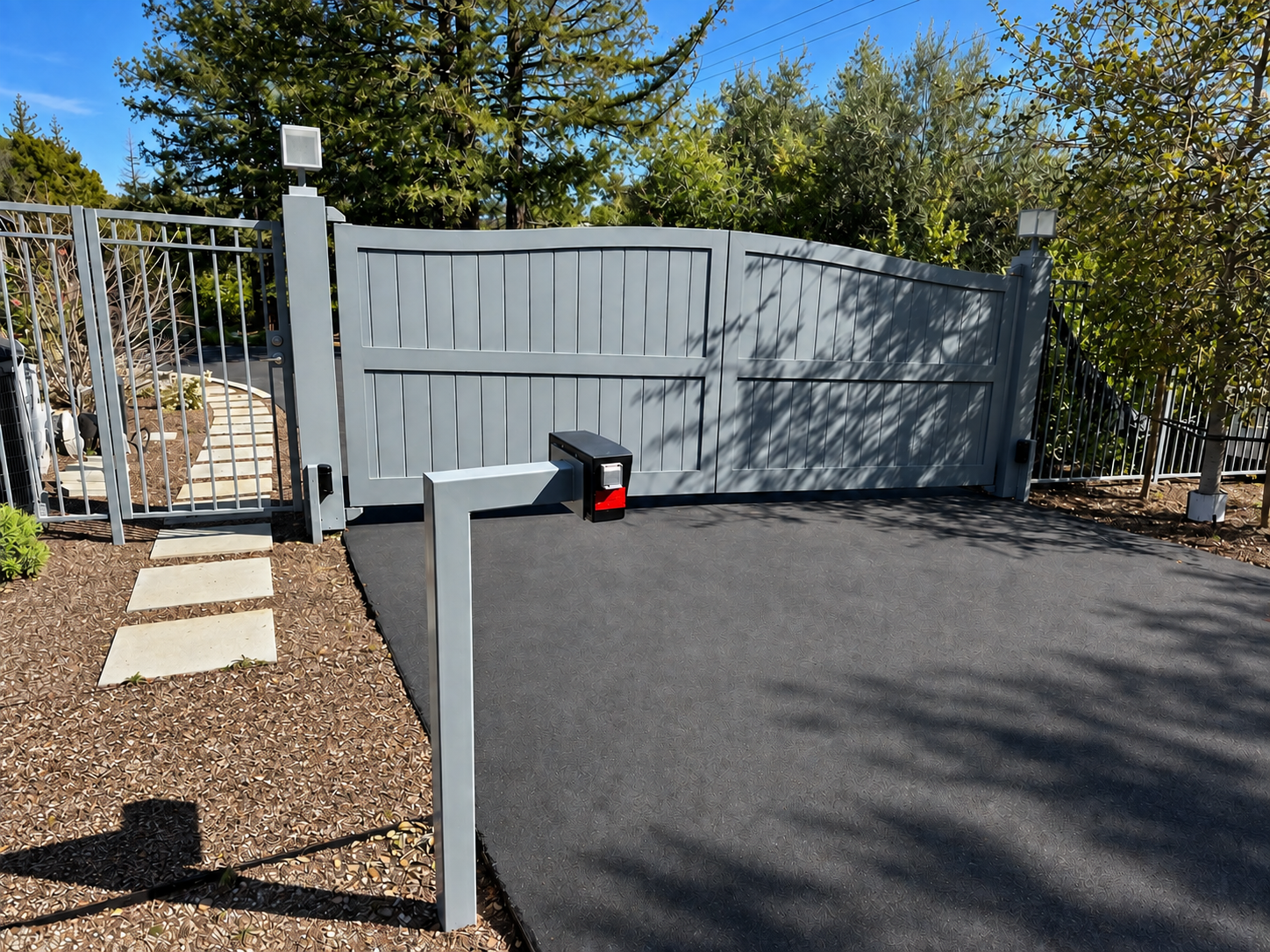 Gray driveway gate with vertical panel design and side pedestrian gate