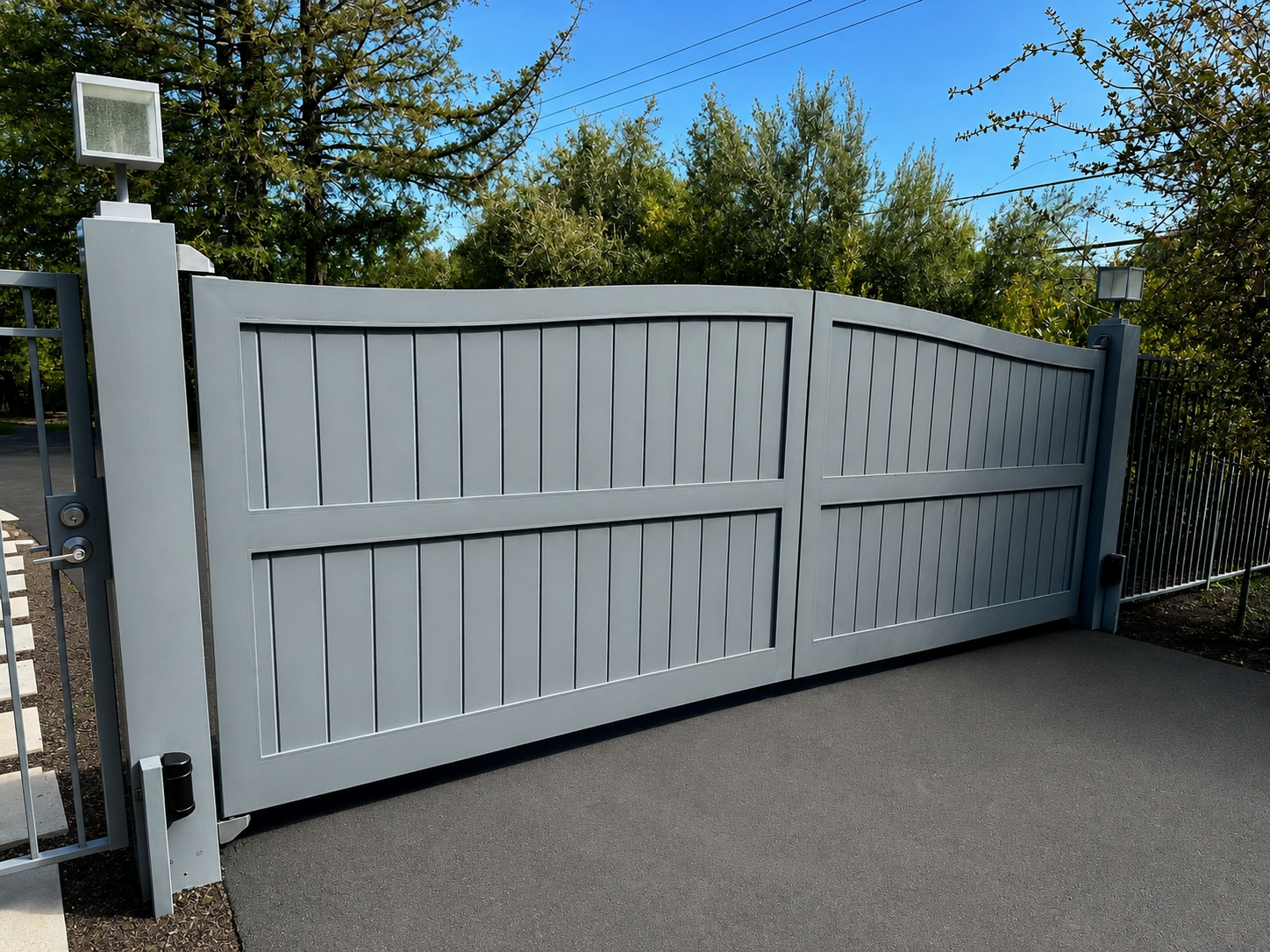 Gray driveway gate with vertical panel design and side pedestrian gate