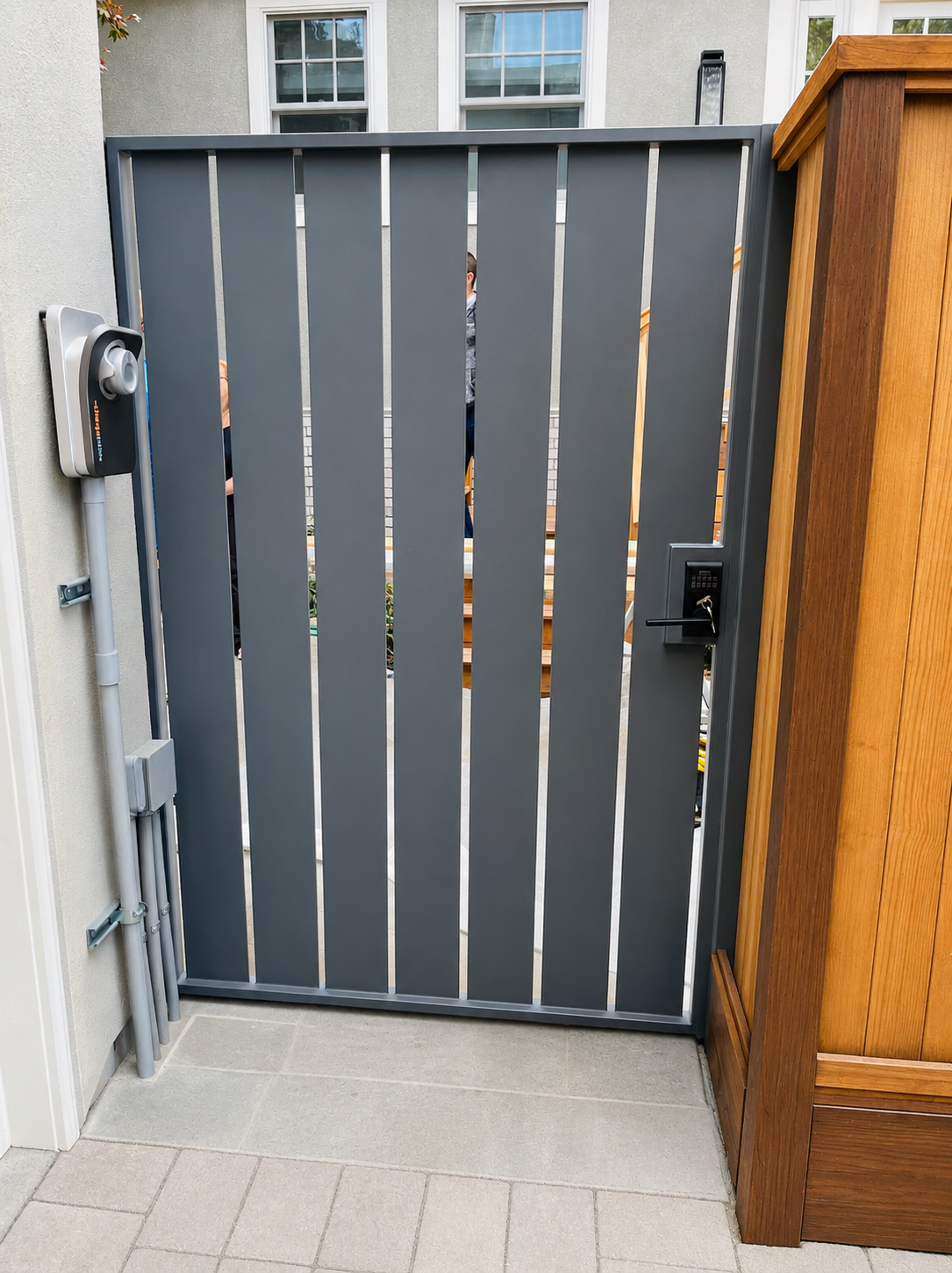 Gray metal side gate with vertical panels and keypad lock