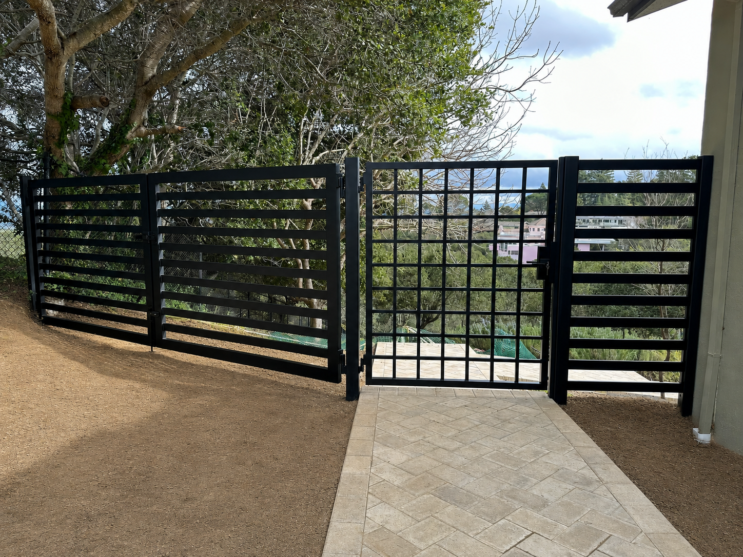 Black hillside gate viewed from paved entry path