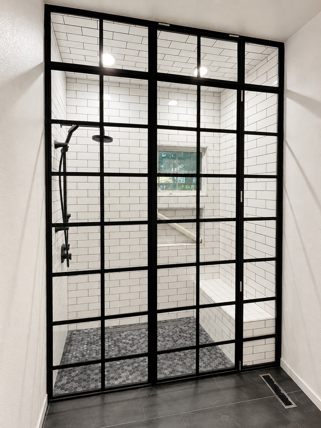Black grid metal and glass shower enclosure with white tile walls