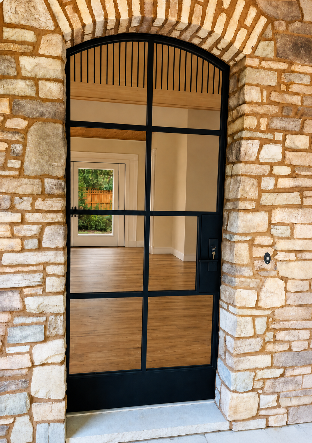 Close front view of black arched glass metal door inside stone entry
