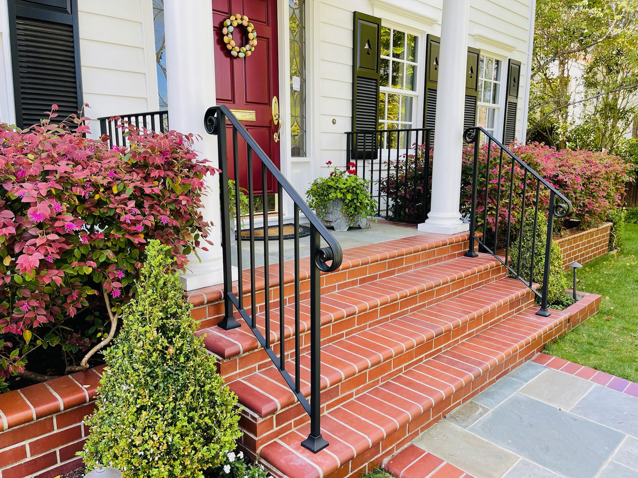 Black entry handrails with curled ends on red brick front steps