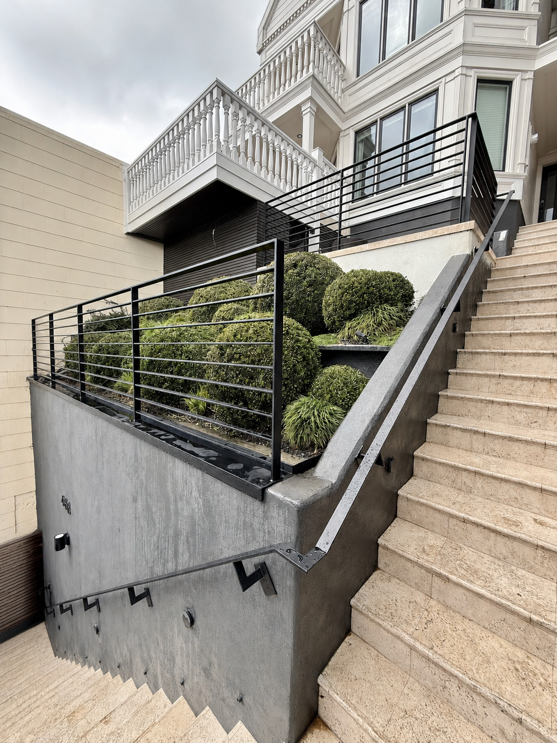 Exterior stair handrail with black railings beside stone steps