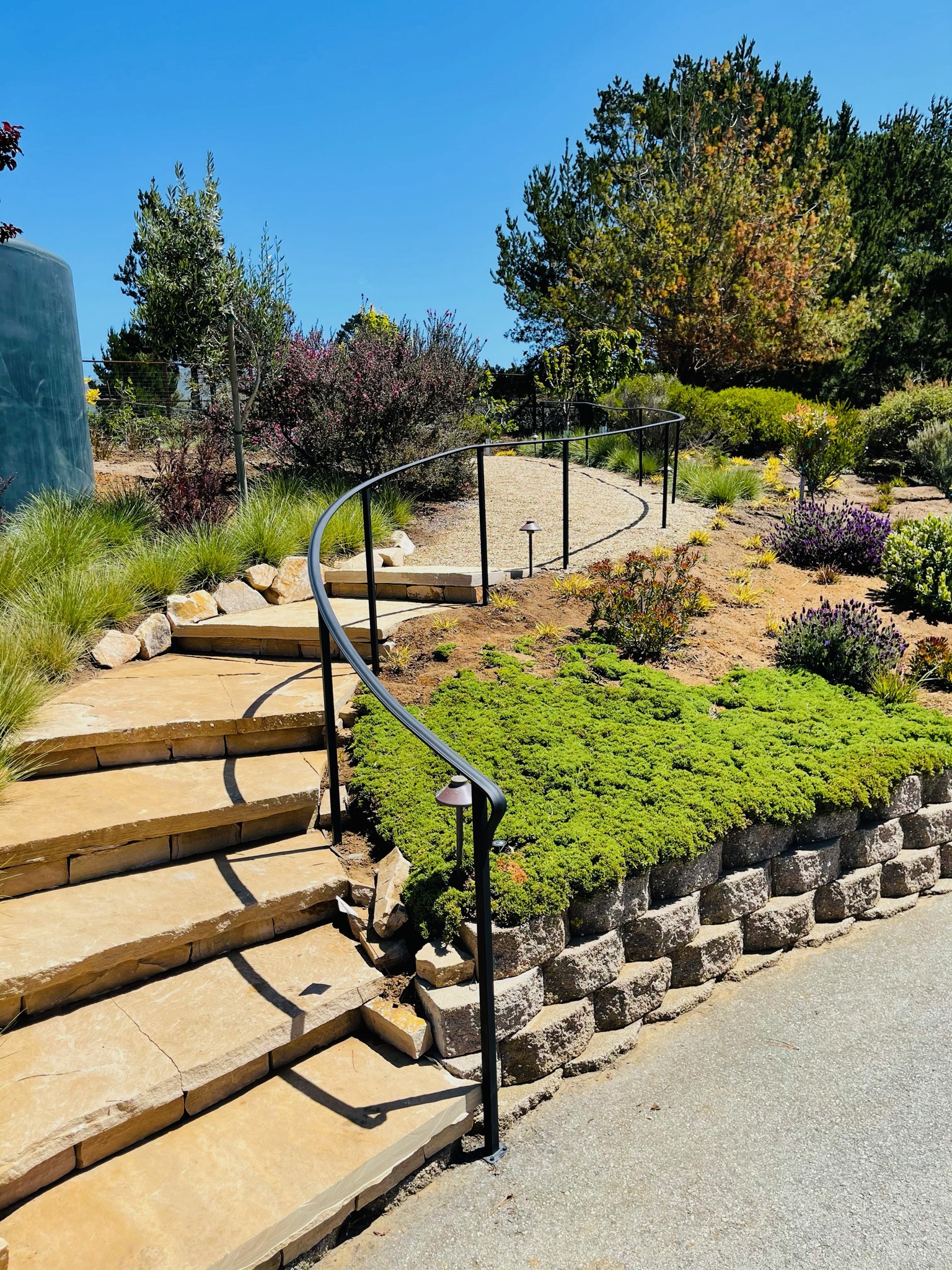 Curved black handrail following landscaped garden steps