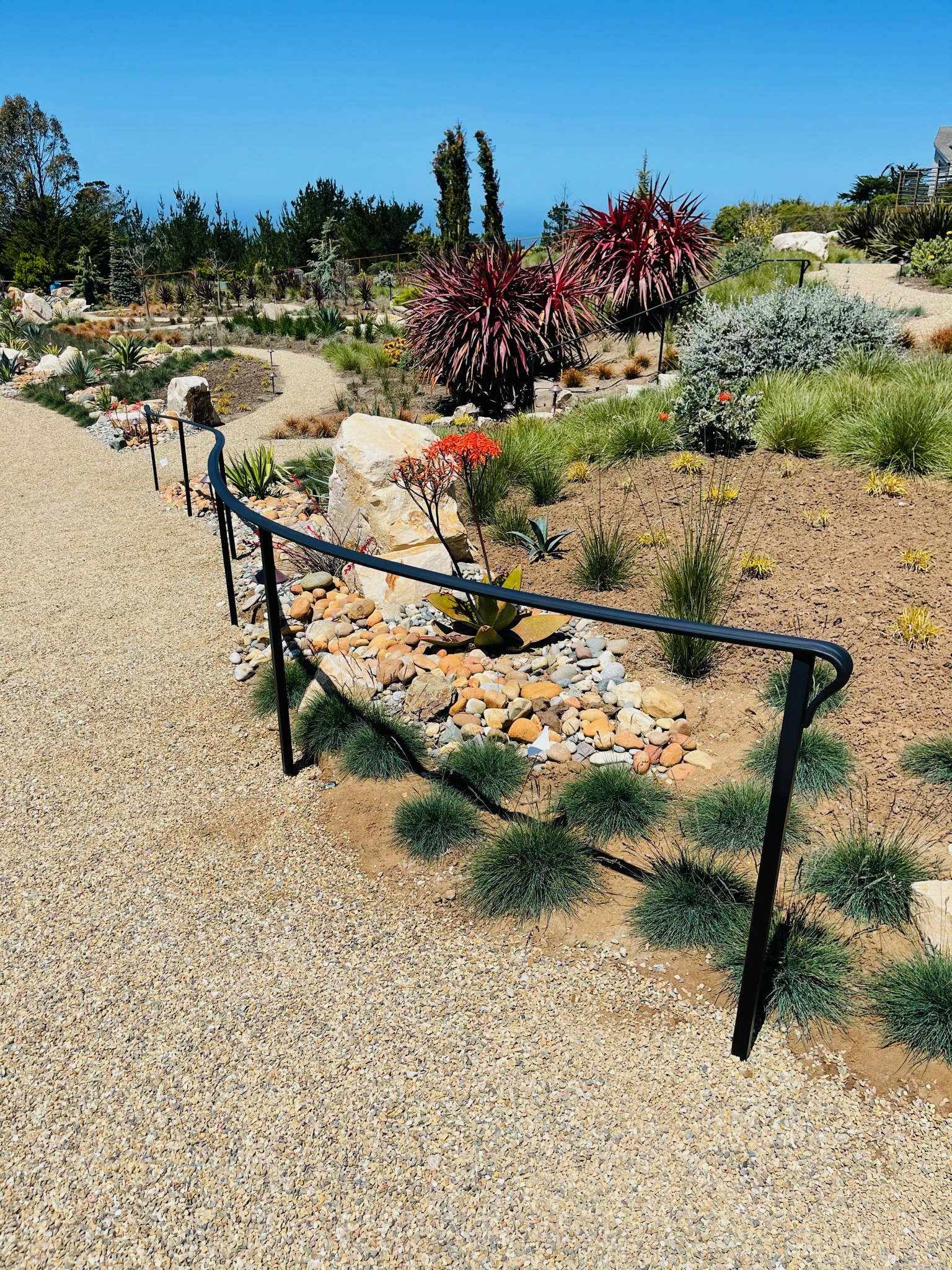 Black garden handrail along a gravel path