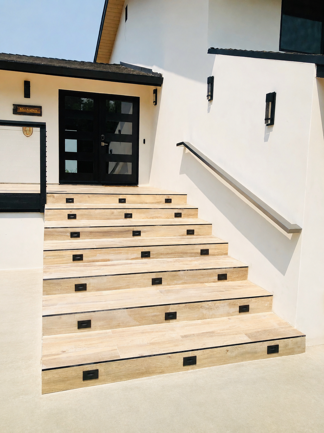 Wide exterior stair with stainless steel wall-mounted handrail