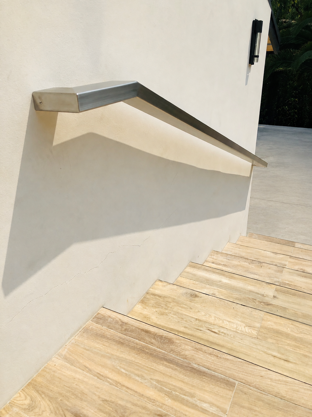 Close view of stainless steel handrail mounted to exterior stucco wall