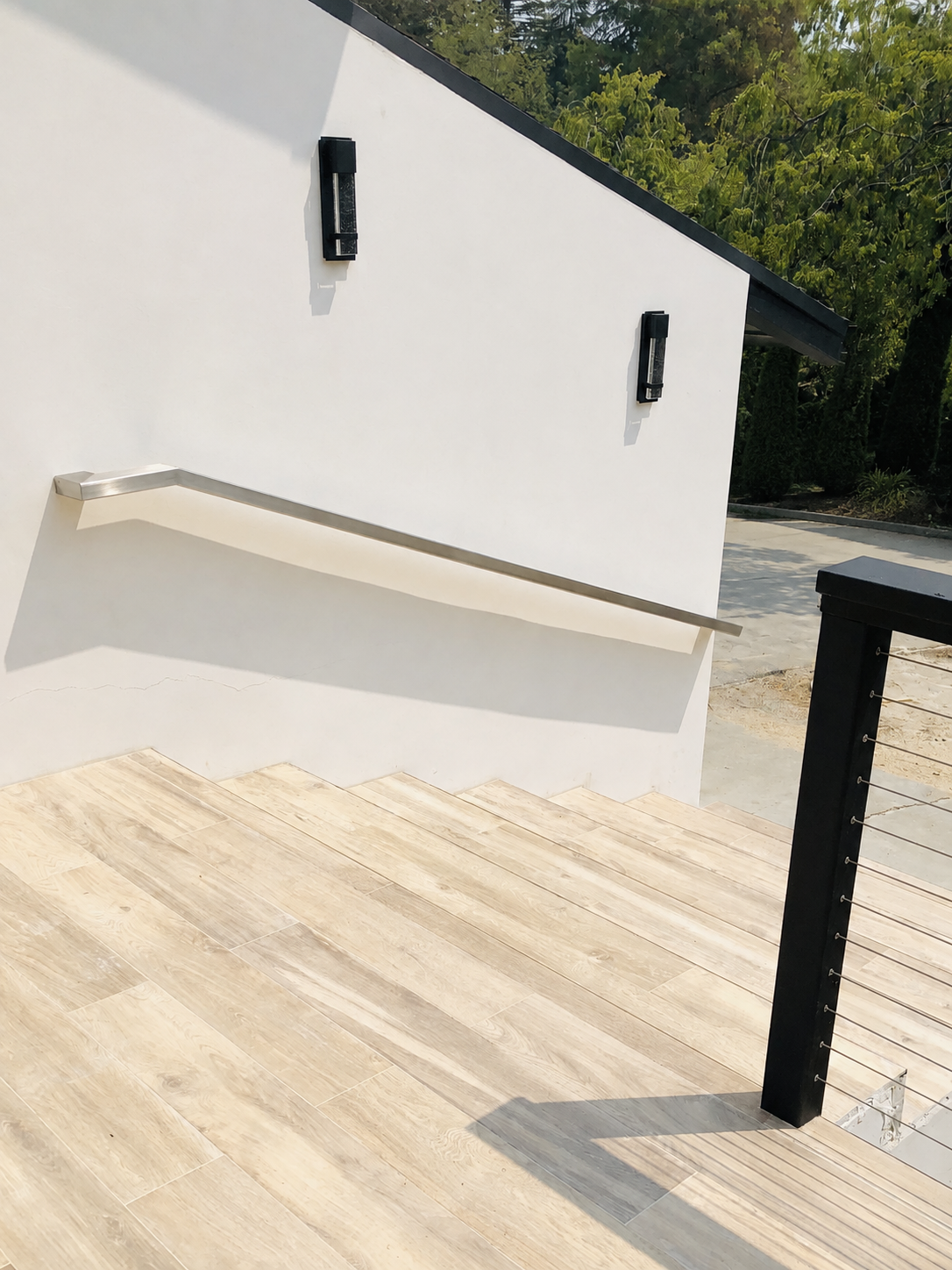 Stainless steel exterior stair handrail beside light wood-look steps