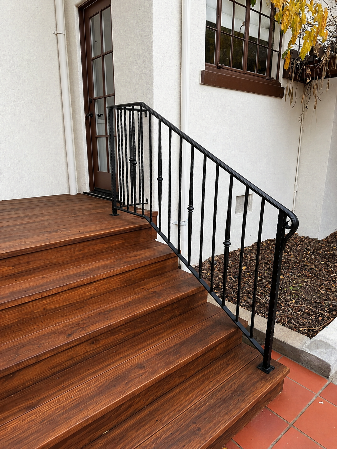 Black decorative railing along polished wood exterior stairs