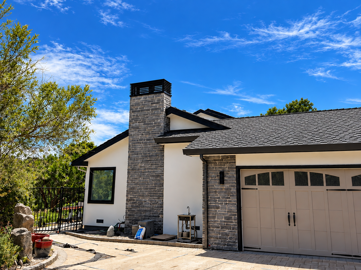 Residential stone chimney with black custom metal chimney cap above a tiled roof