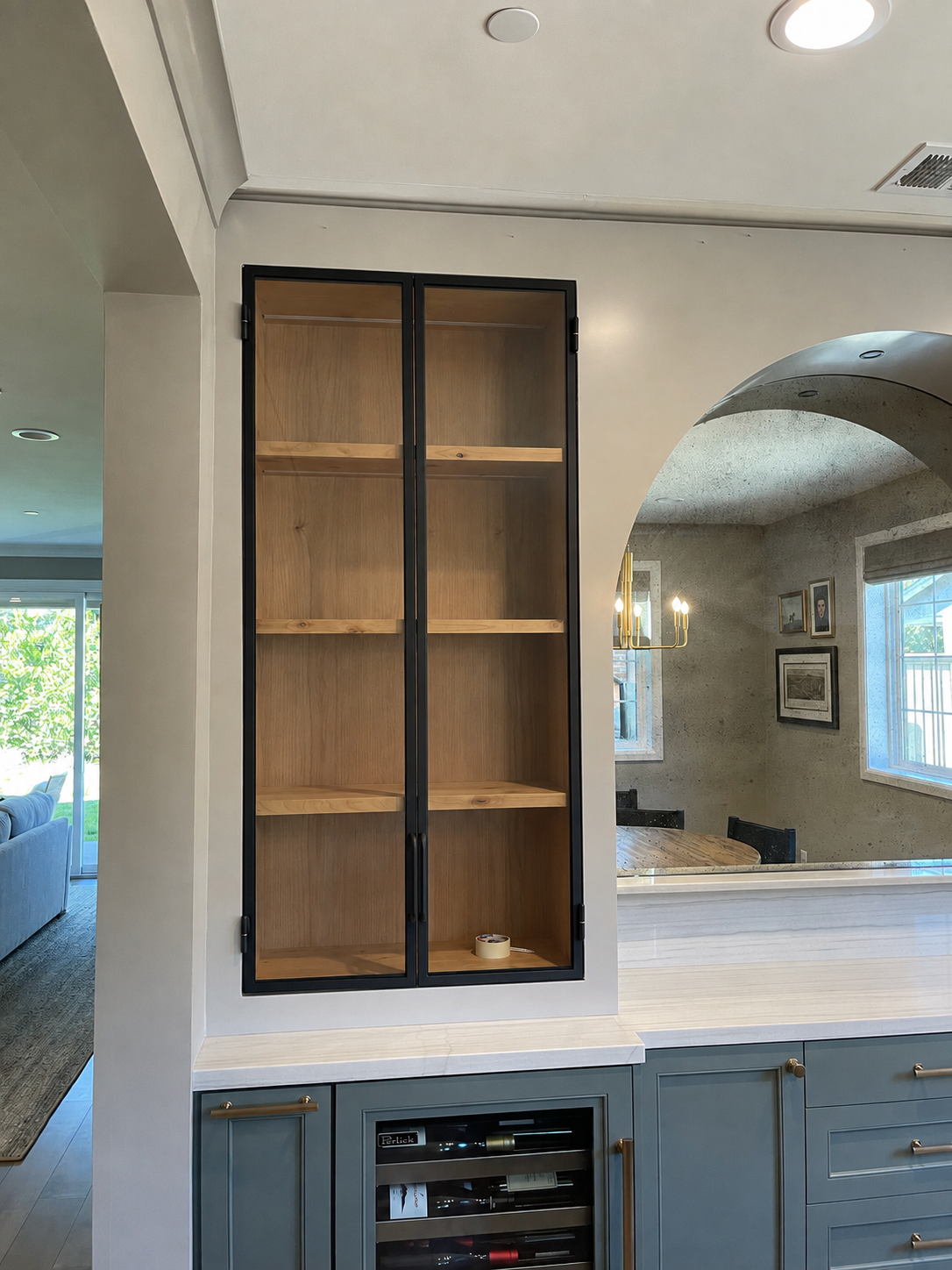 Black metal and glass cabinet beside an arched mirror and built-in bar counter