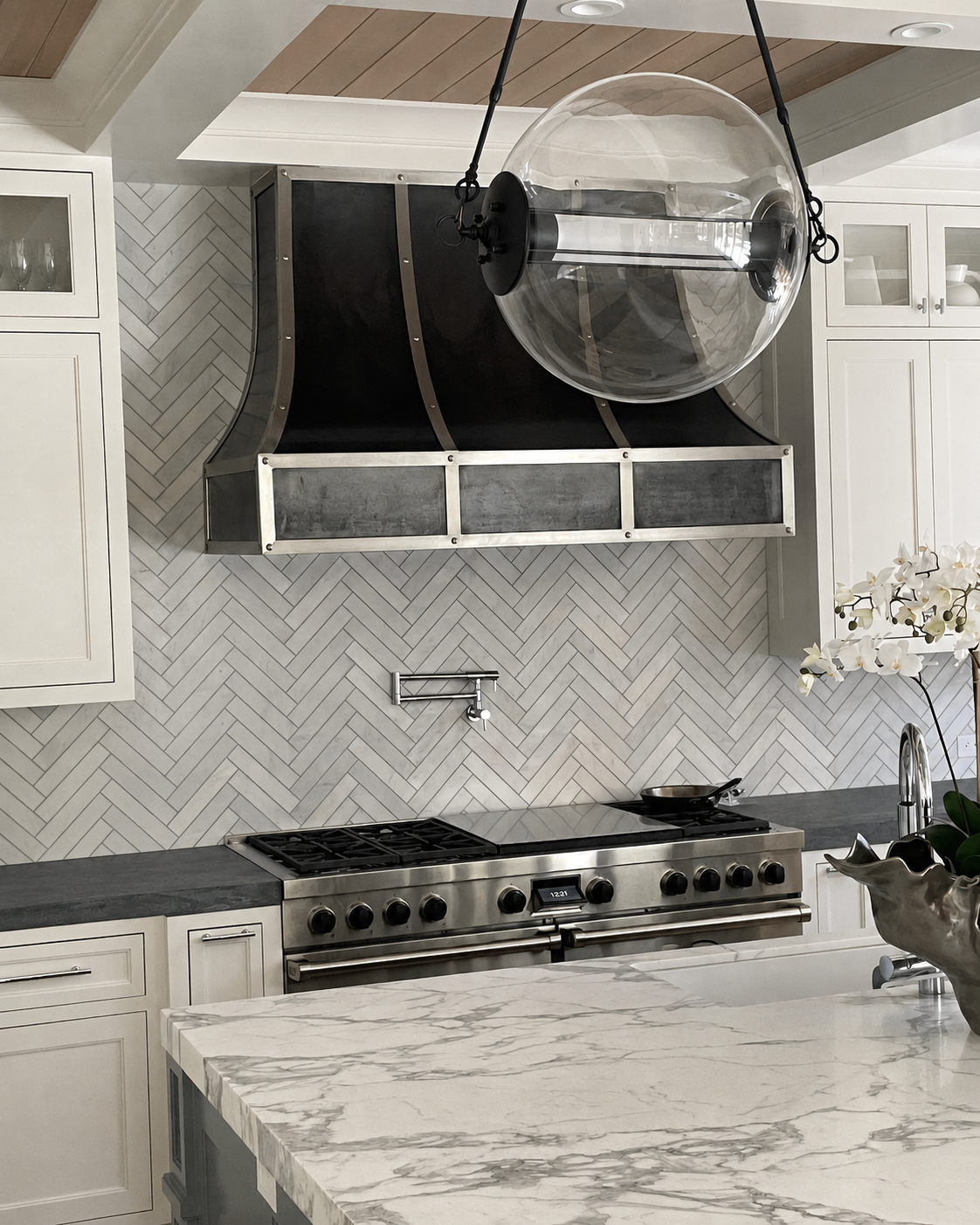 Custom black and stainless steel kitchen range hood above a stove
