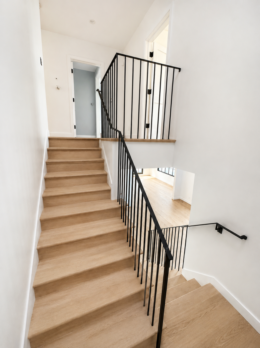 Stair landing with black railing and light wood treads