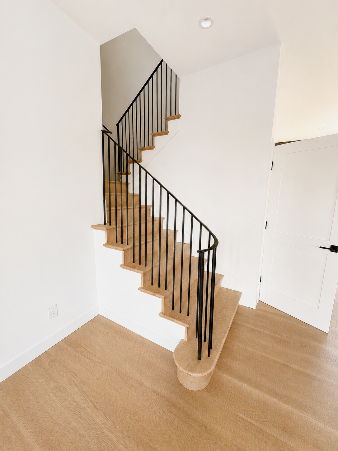 Light wood staircase with black vertical railing