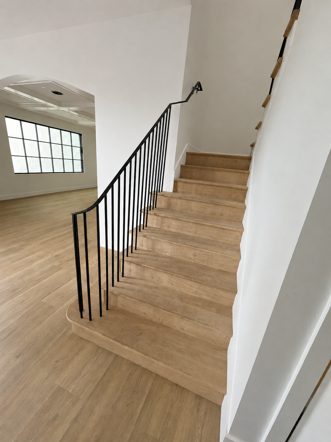 Light wood staircase with curved black stair railing