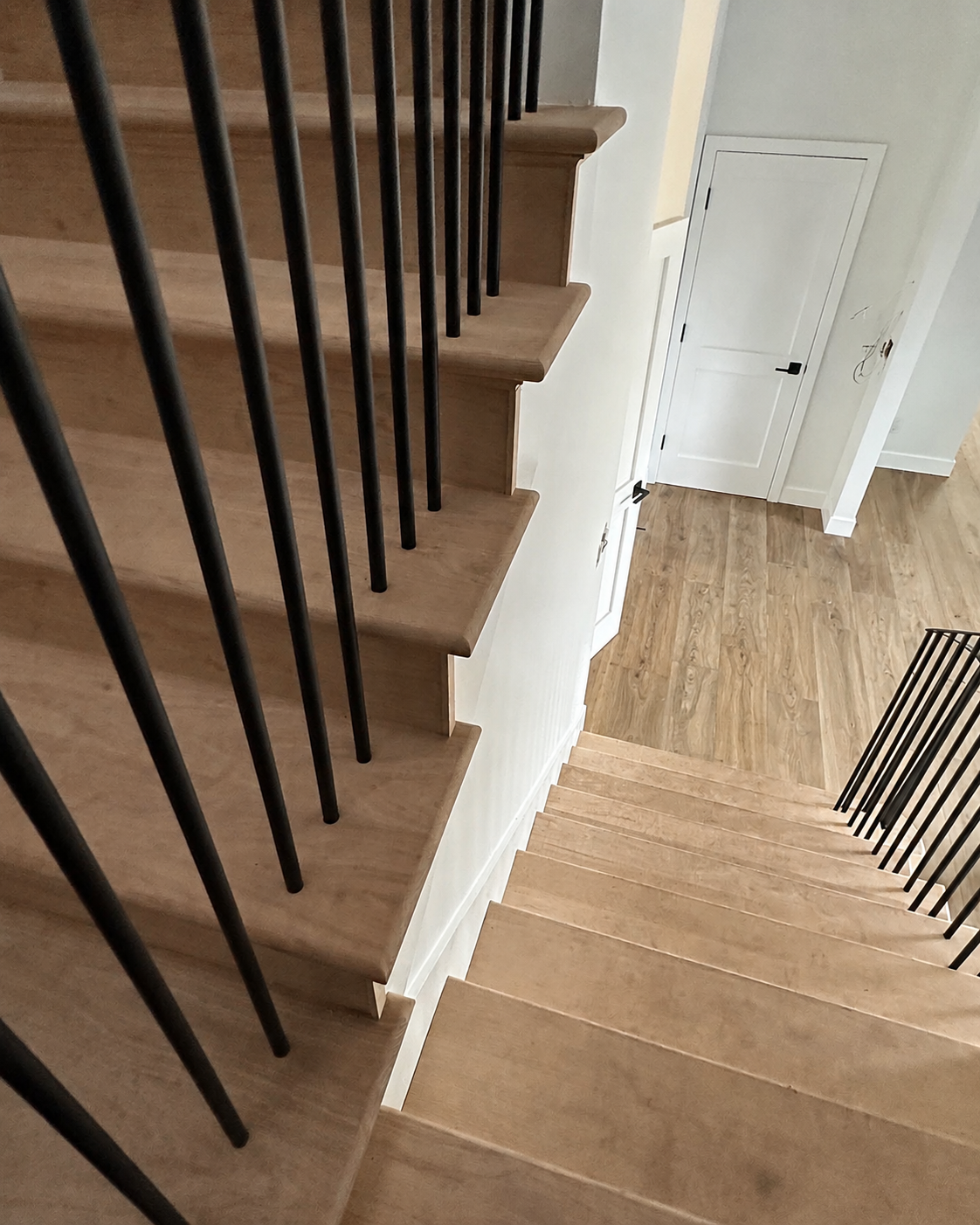 Close view of wood stairs and black railing balusters
