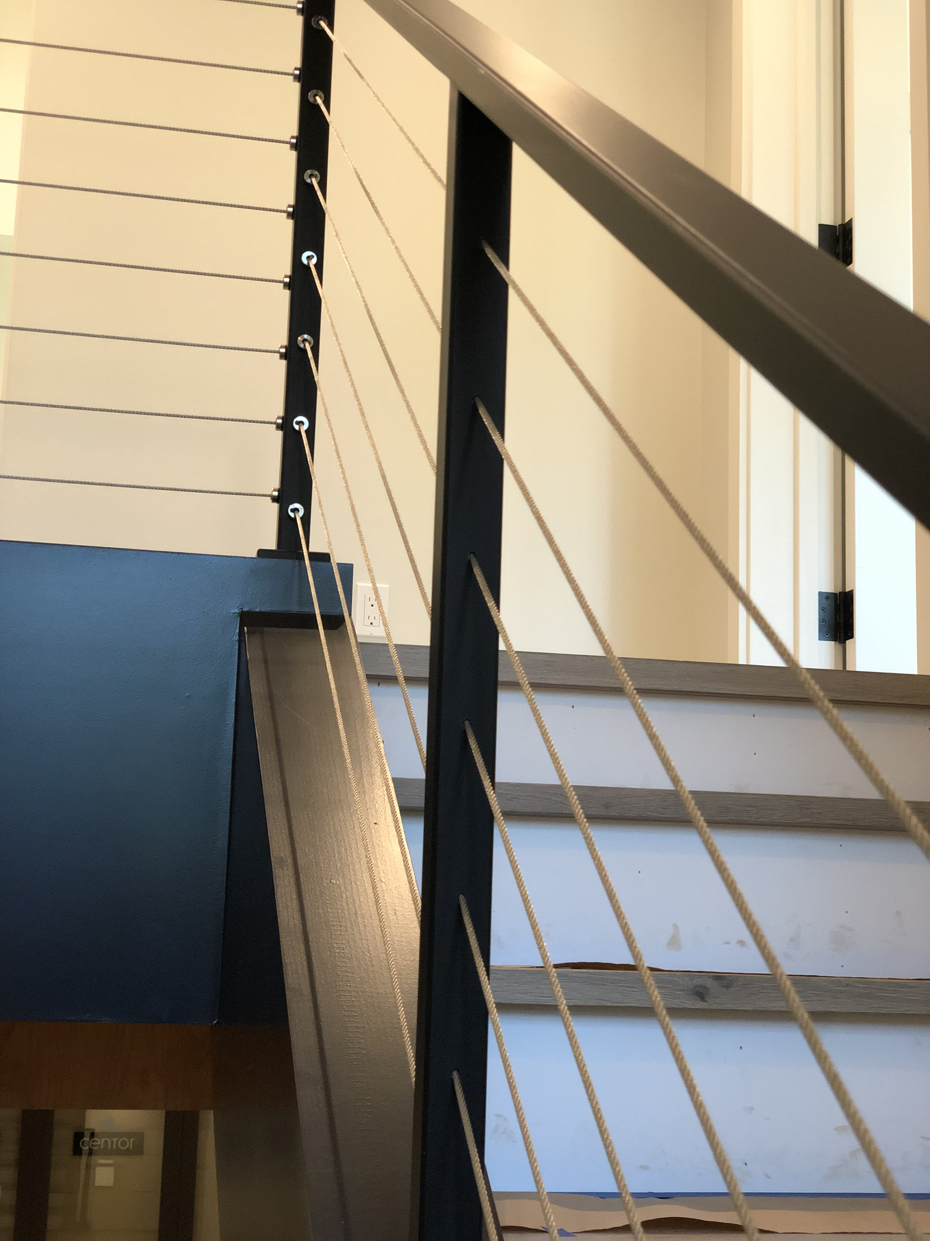 Close-up cable railing detail with black steel post