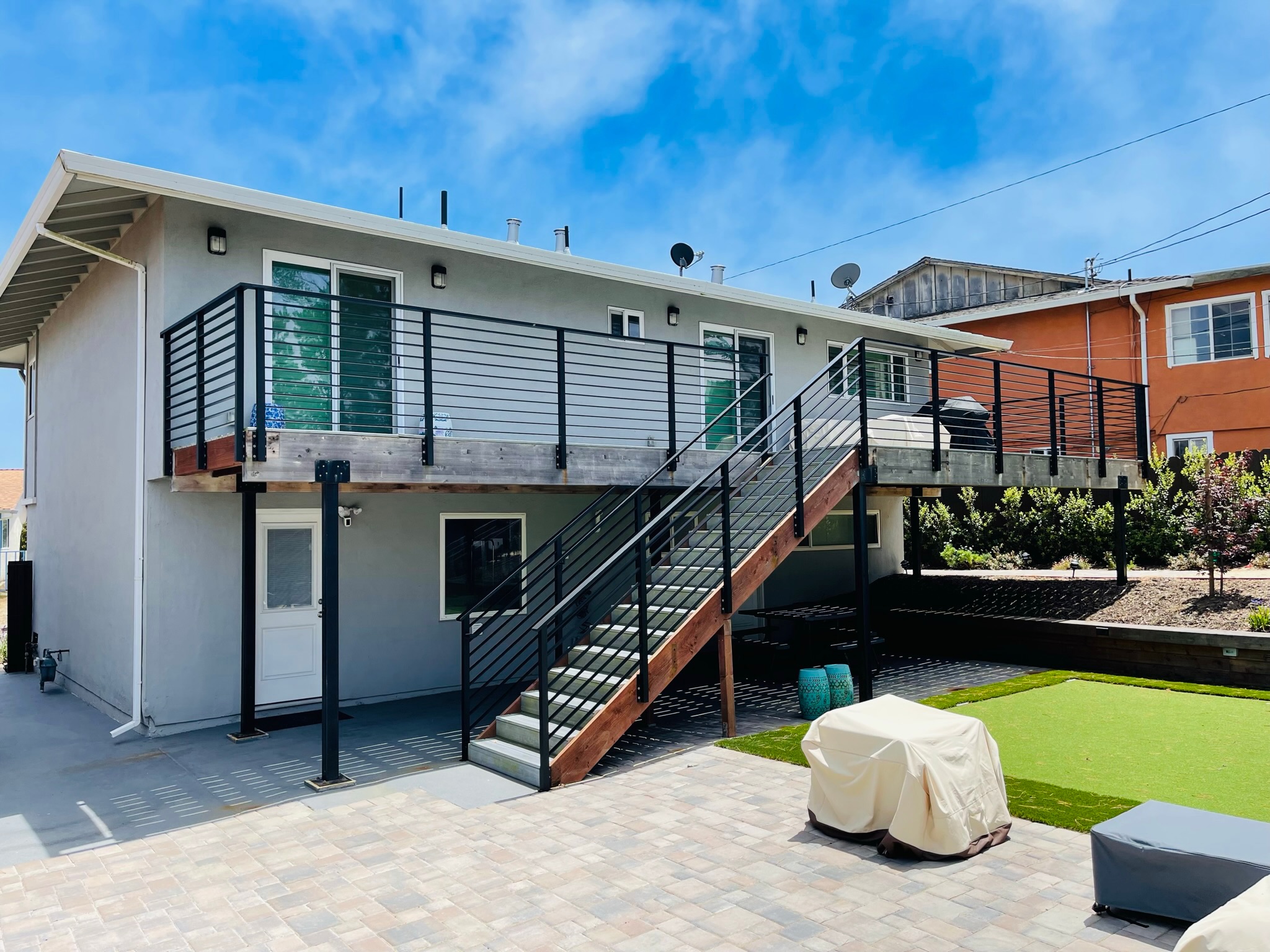 Backyard deck with black metal railing and exterior stair