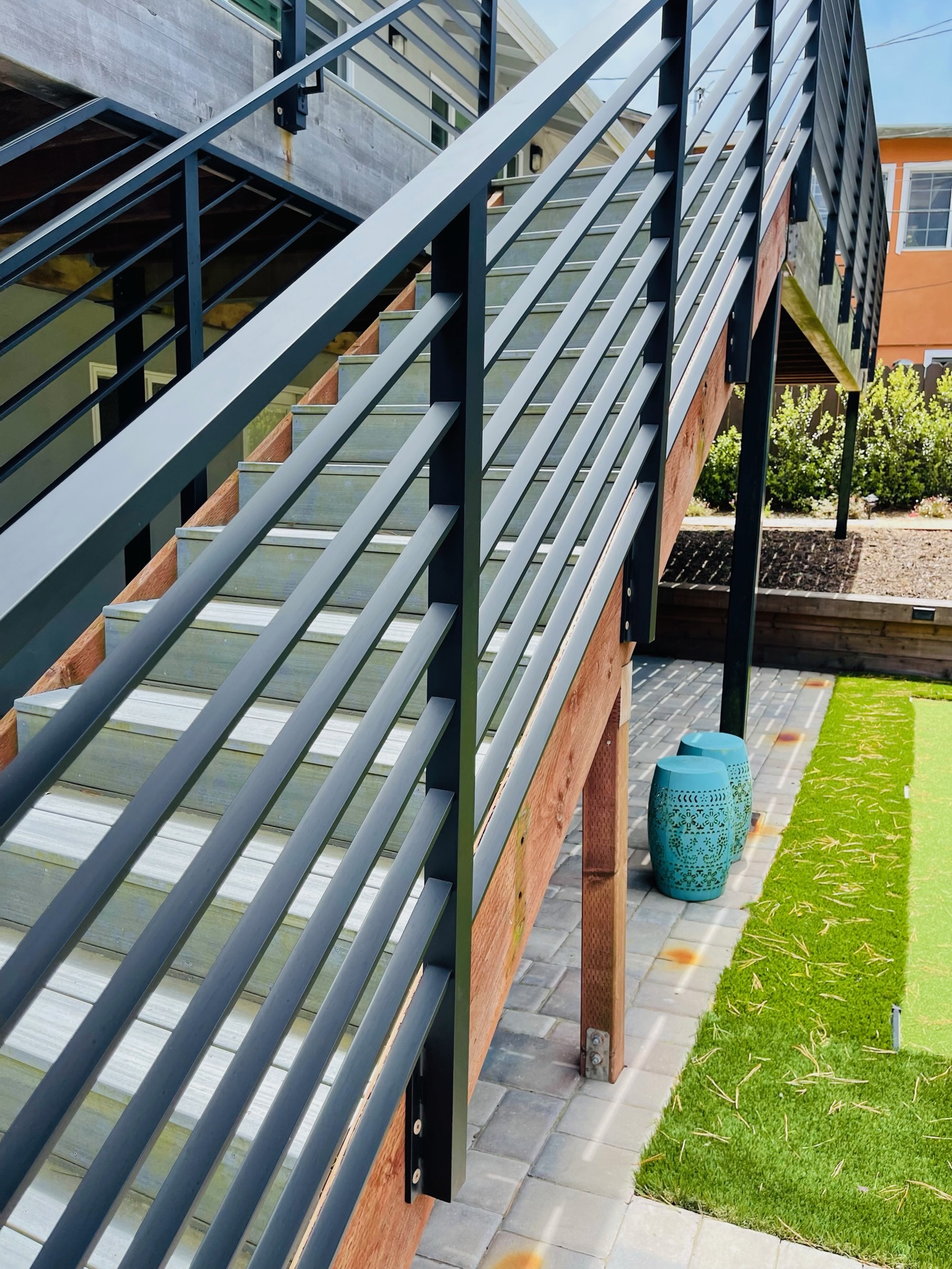 Close view of black exterior railing along wood stair and deck