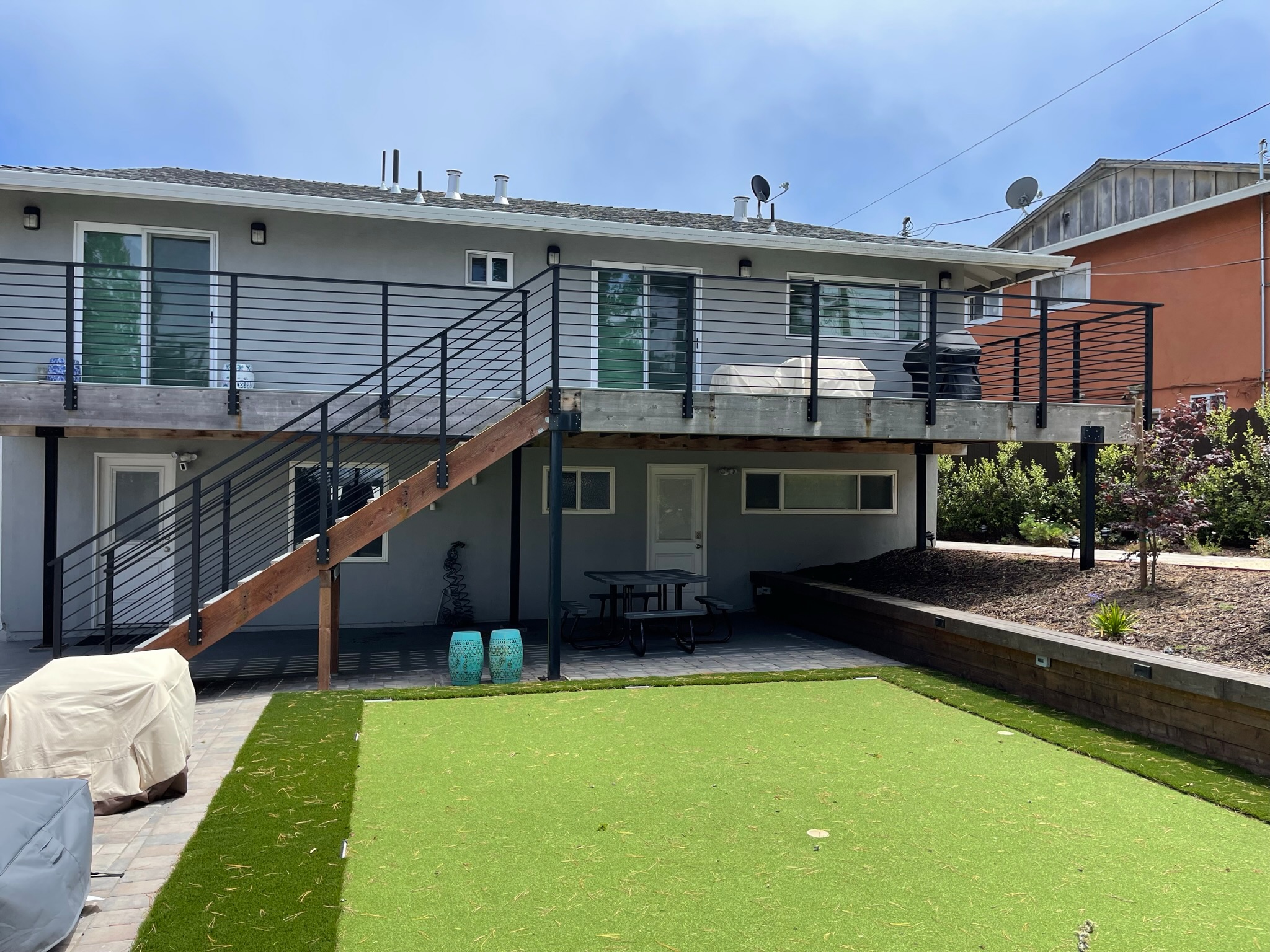 Wide backyard view with black deck railing and stair railing