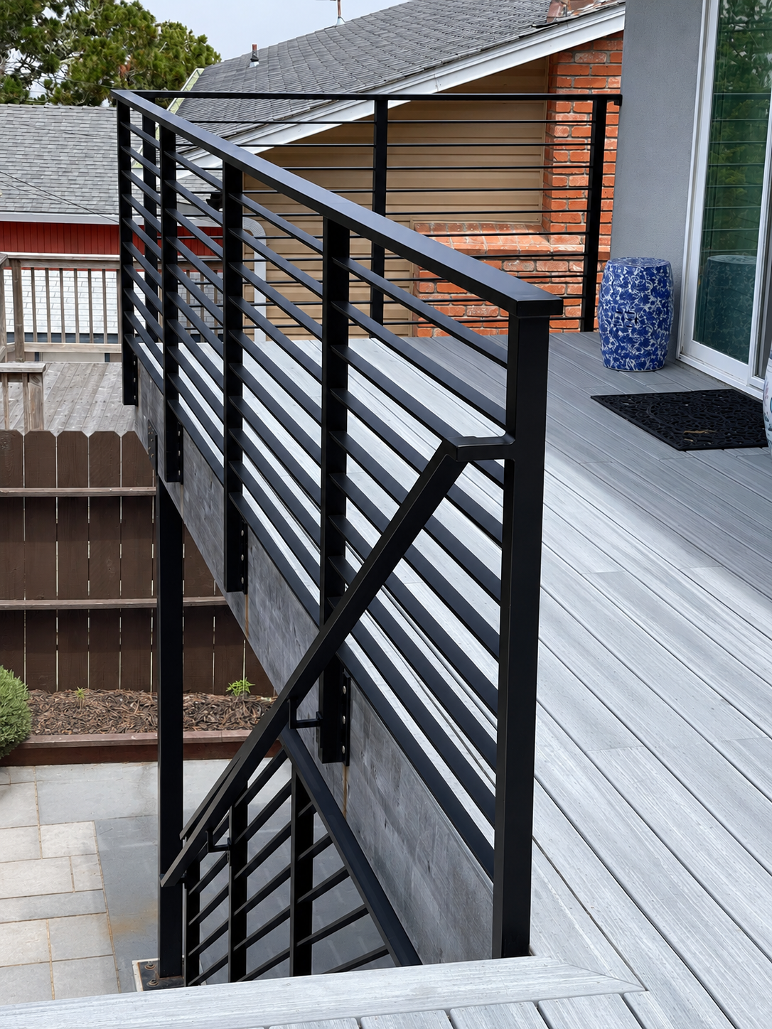 Black horizontal deck railing beside gray deck boards