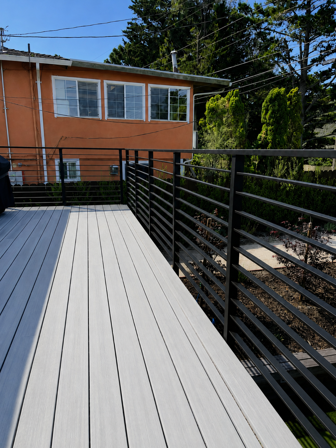 Black deck railing overlooking a landscaped backyard