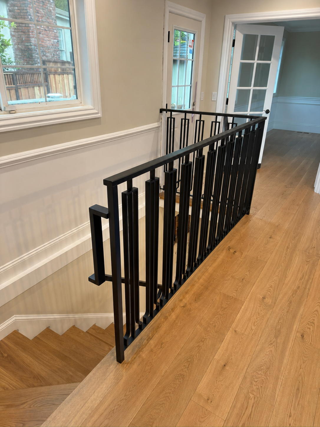 Black railing along upper wood floor hallway
