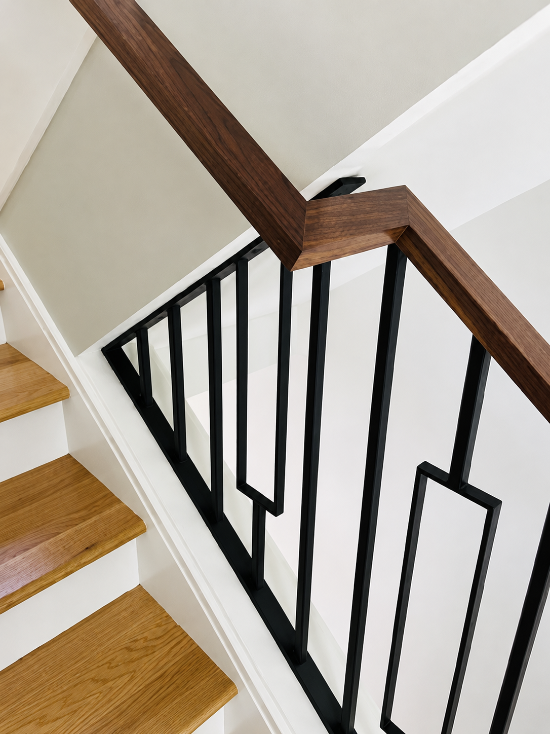 Close detail of black metal stair railing with wood handrail