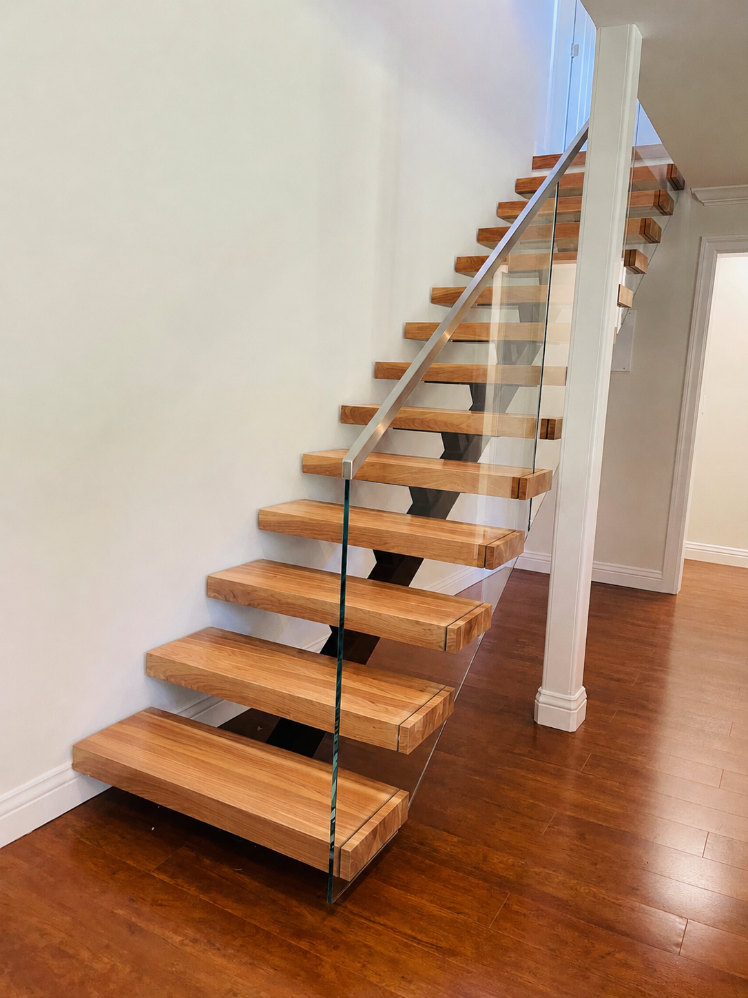 Floating wood staircase with glass railing and light handrail