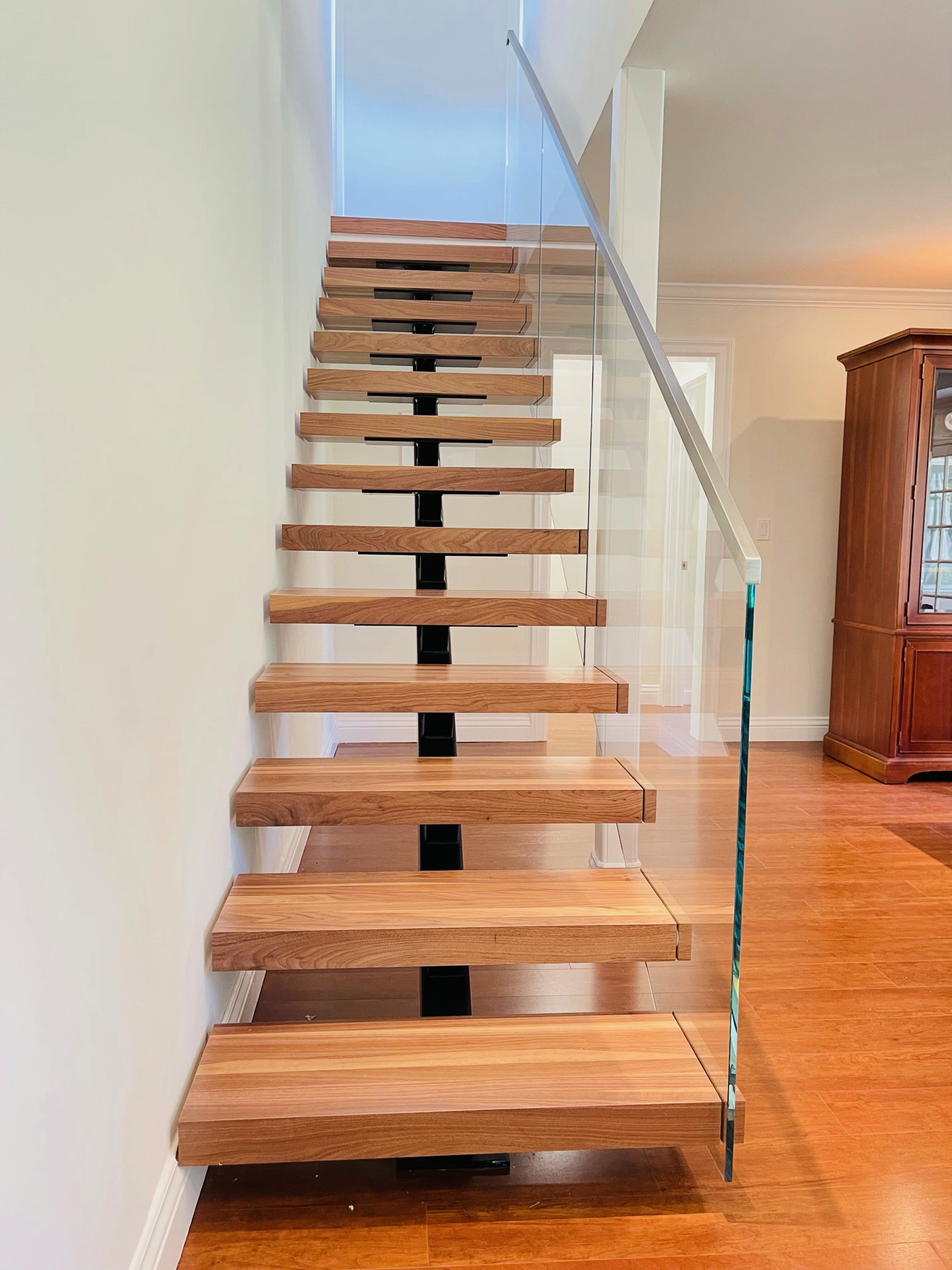 Front view of floating wood staircase with glass railing