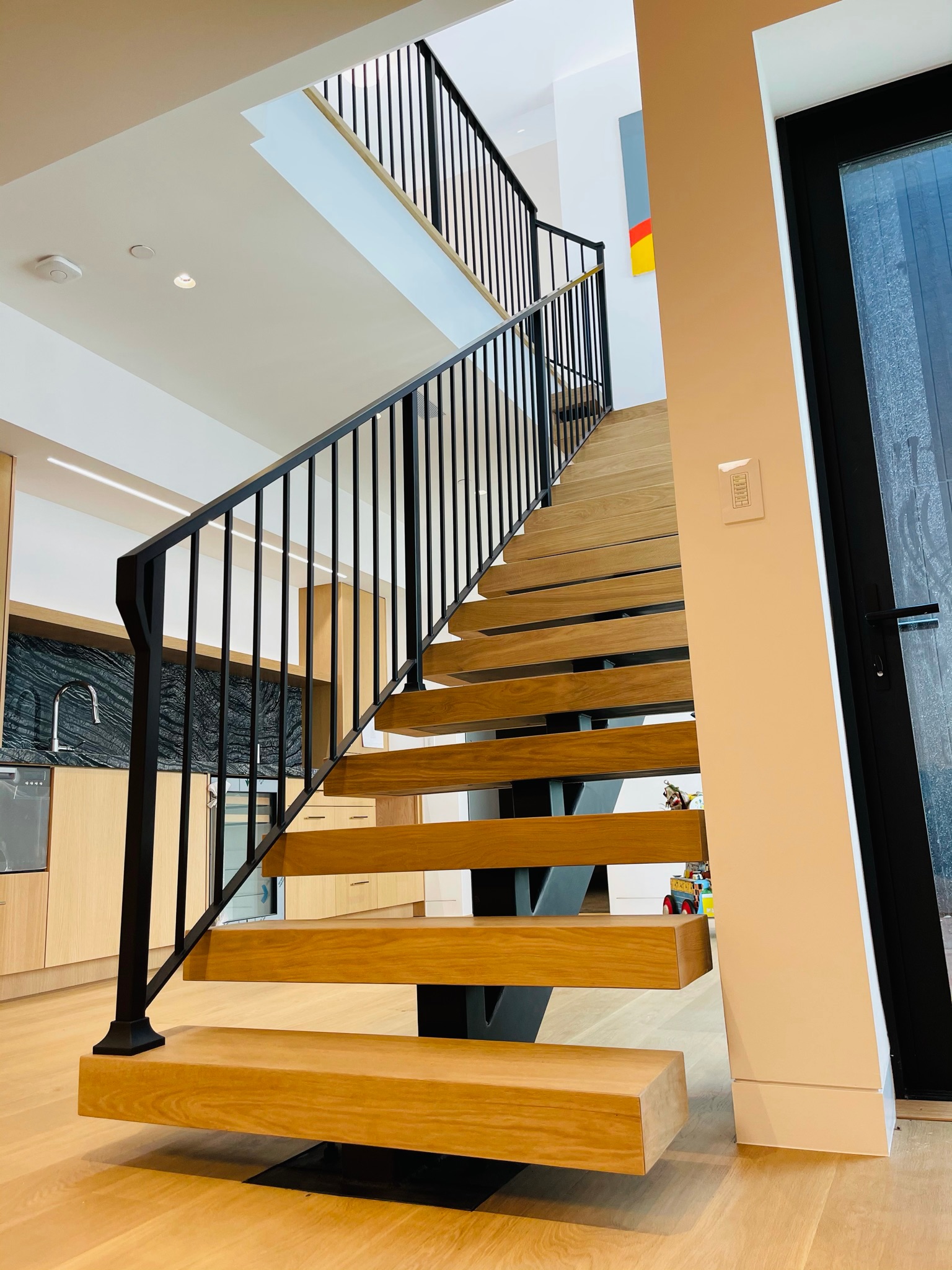 Floating wood stair with black metal railing and open risers