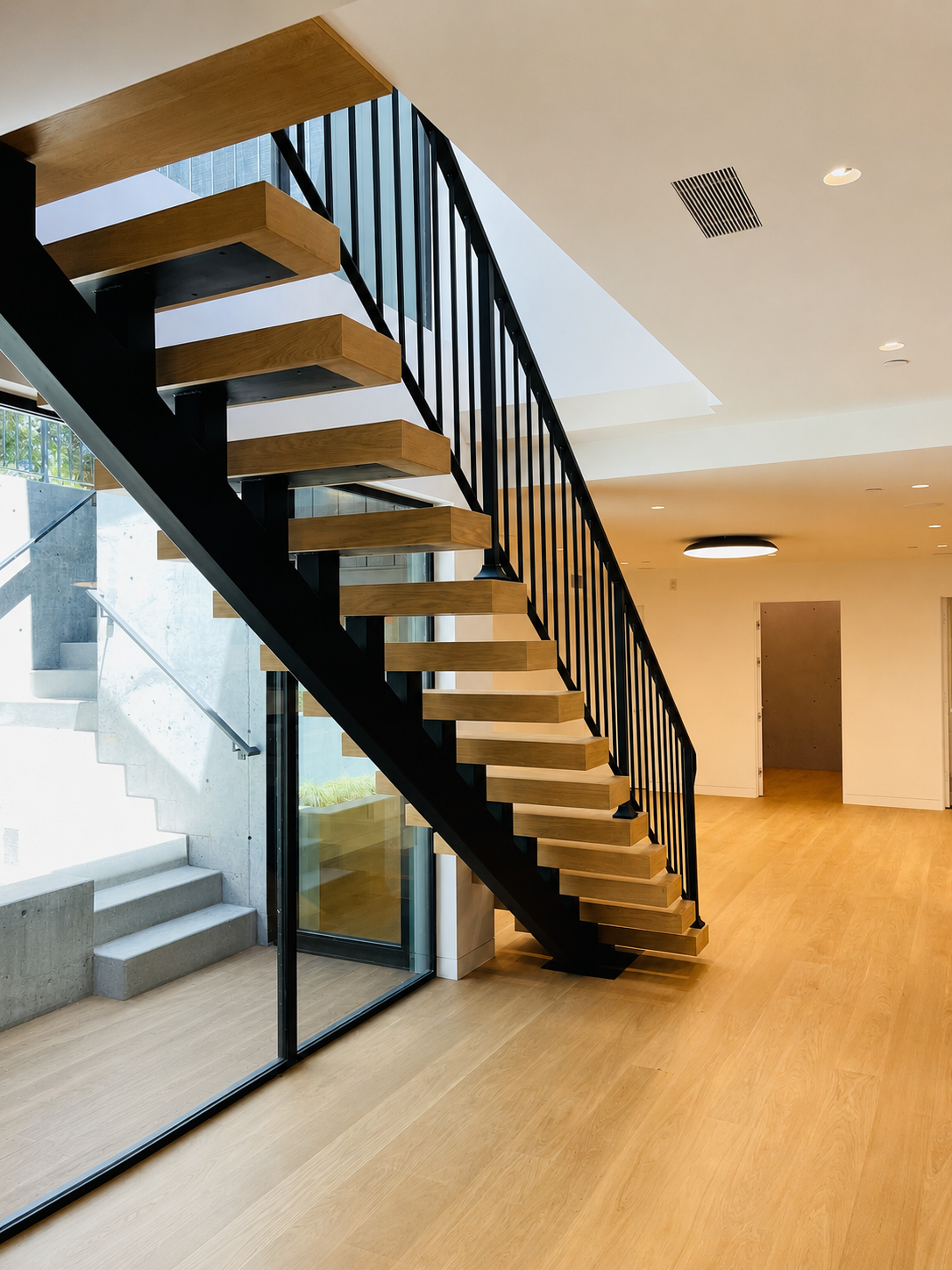 Wide view of floating wood stair with black steel stringer and railing